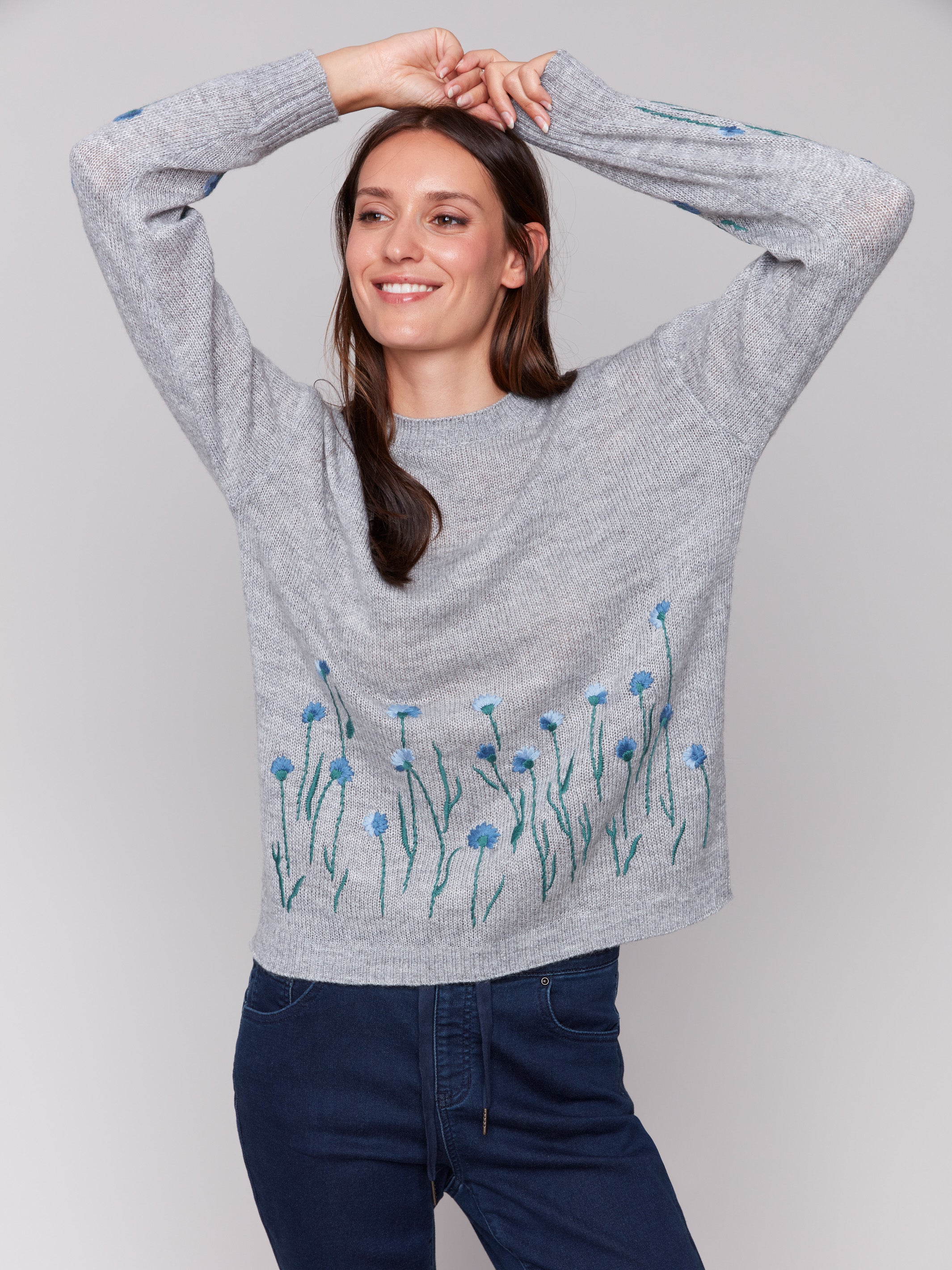 Grey knit sweater with blue floral embroidery along the hem and sleeves, featuring a crew neckline by Charlie B.