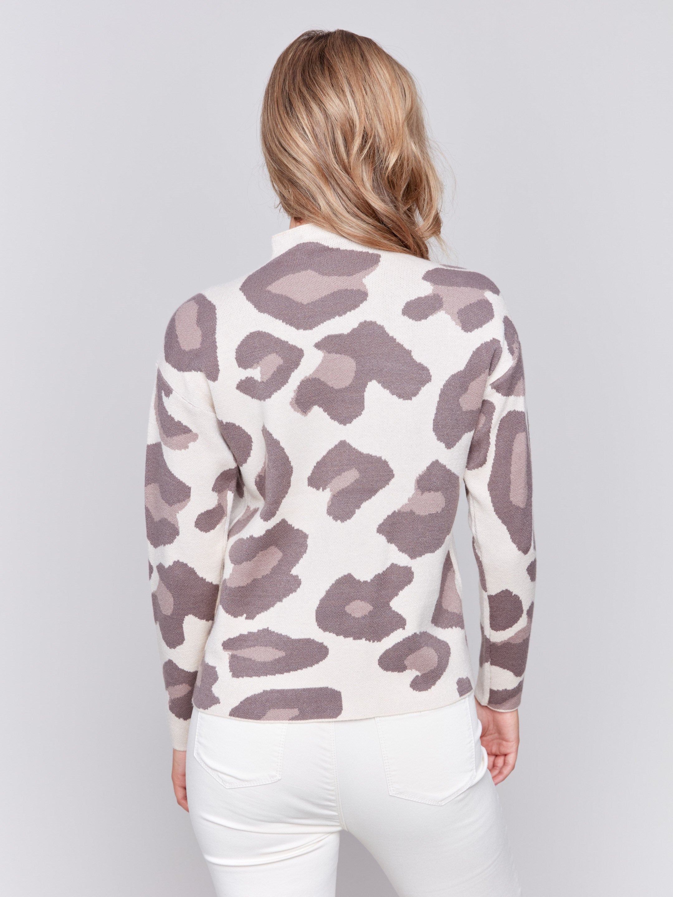 Woman wearing a beige mock neck sweater with a brown animal print by Charlie B.