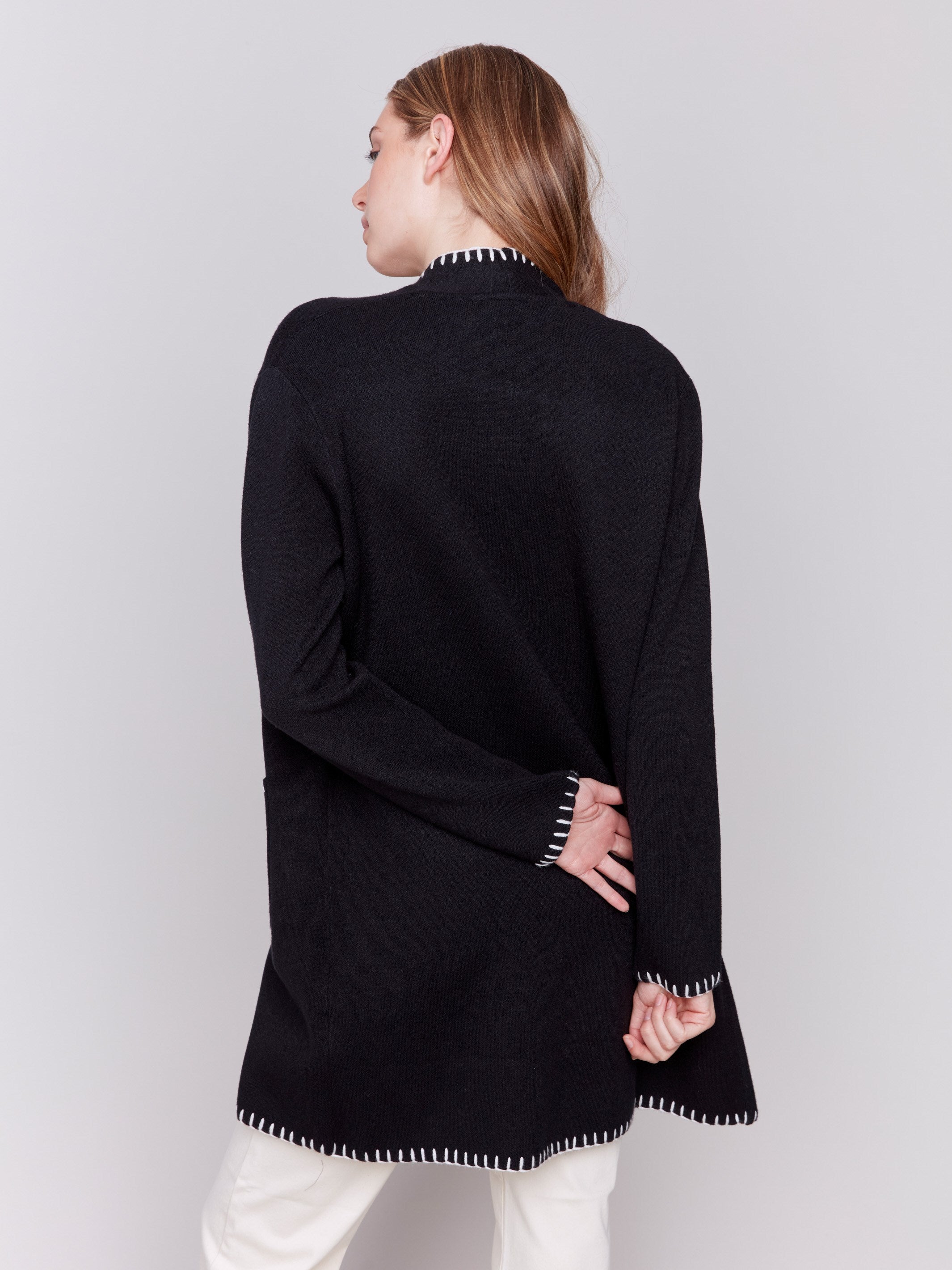 Black long cardigan with white blanket stitch trim, featuring patch pockets and an open front by Charlie B.