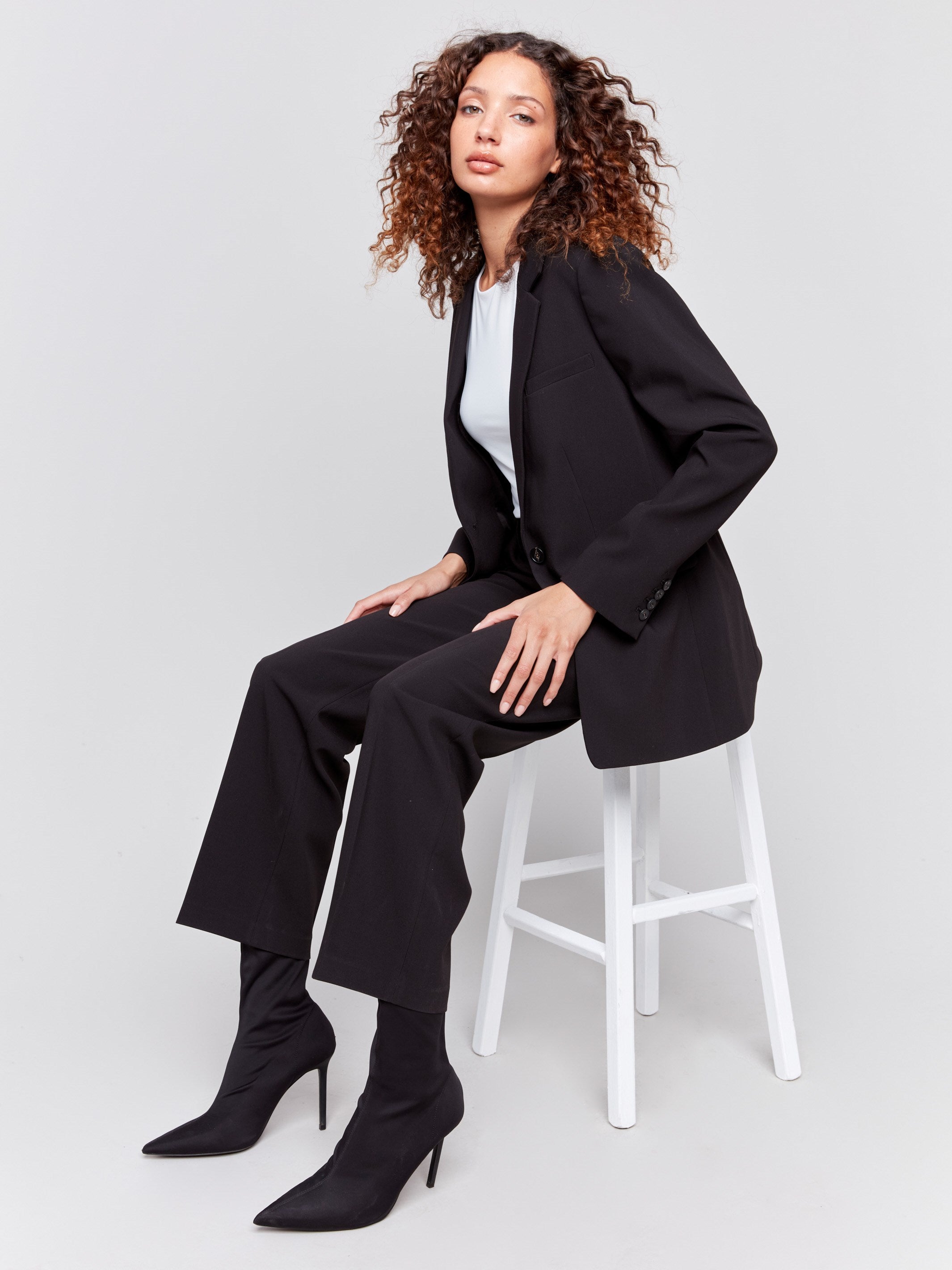 Black blazer featuring a ruched back detail, single button closure, and front flap pockets by Charlie B.