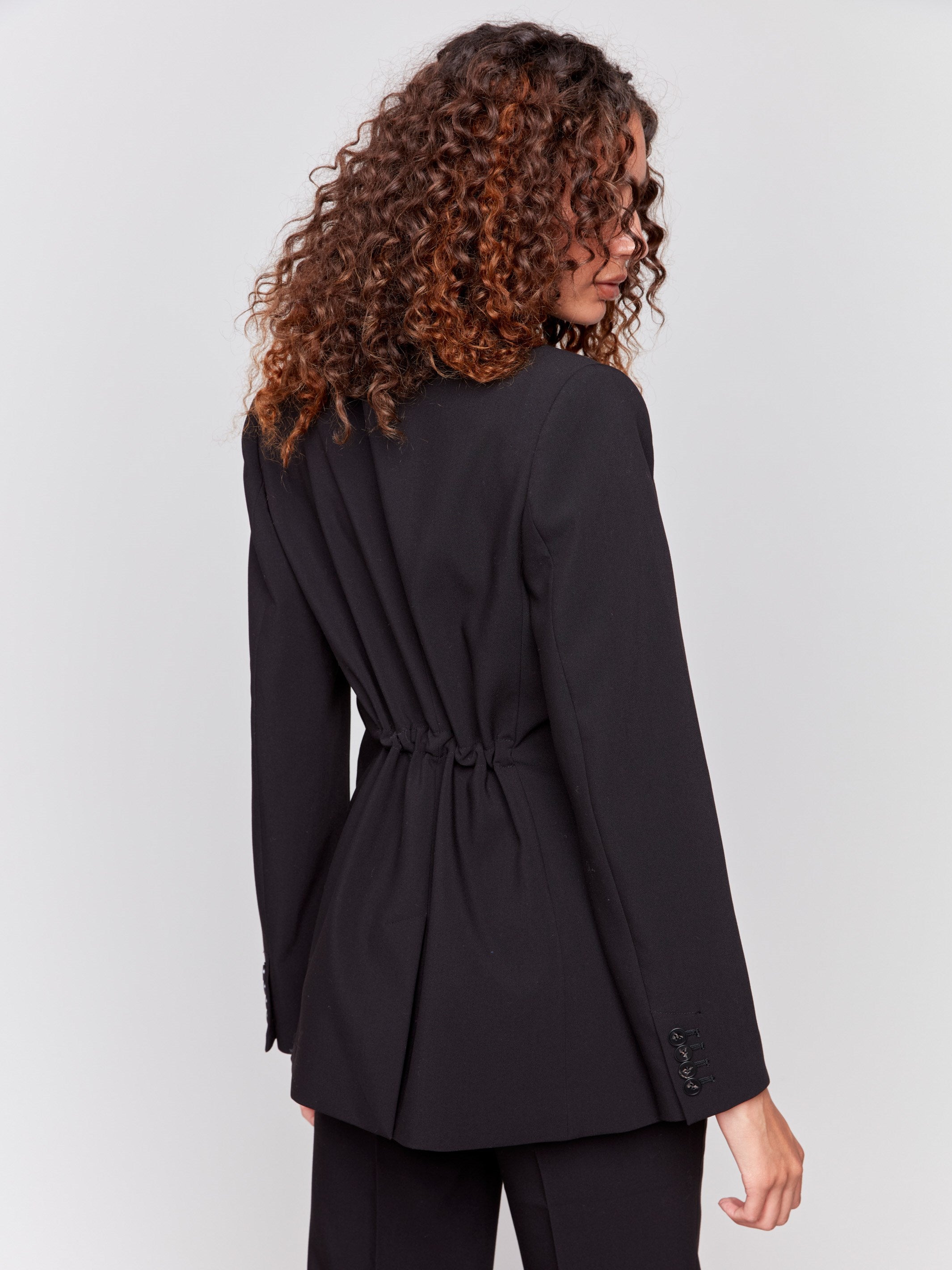 Black blazer featuring a ruched back detail, single button closure, and front flap pockets by Charlie B.