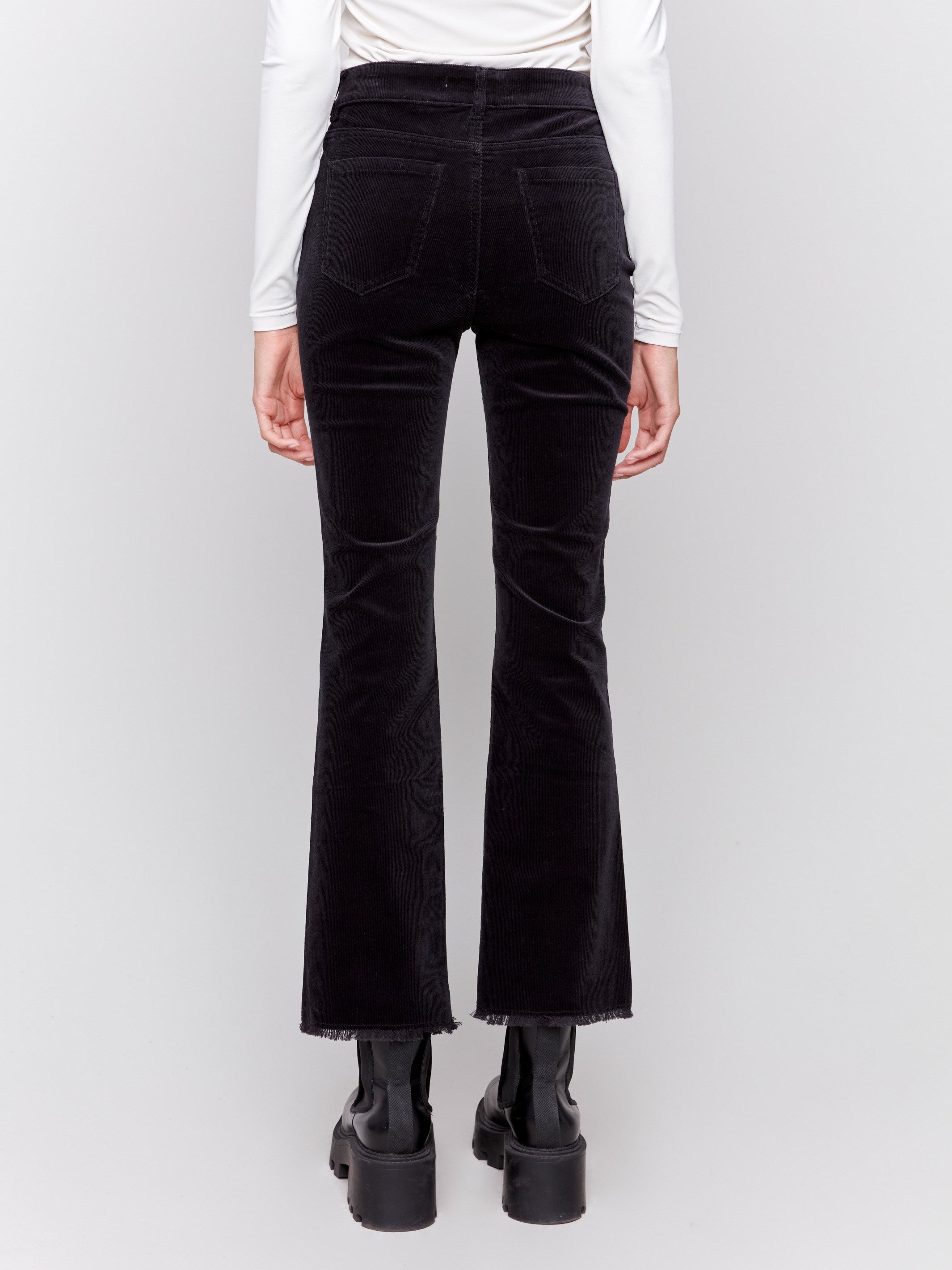 Black bootcut corduroy pants with an asymmetrical frayed hem and a bootcut fit by Charlie B.