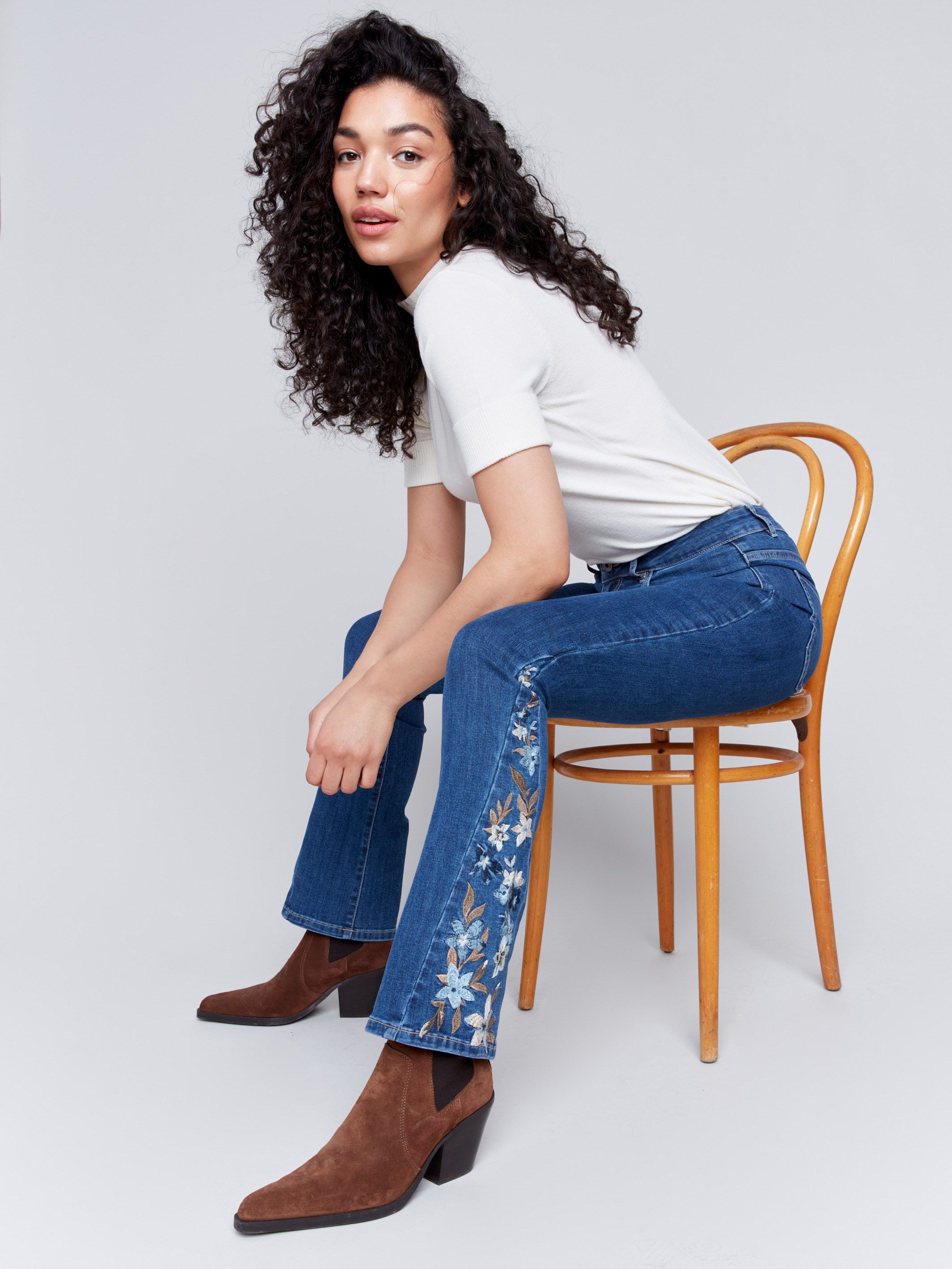 Indigo blue bootcut jeans with vibrant floral embroidery on the sides and a classic five-pocket design by Charlie B.