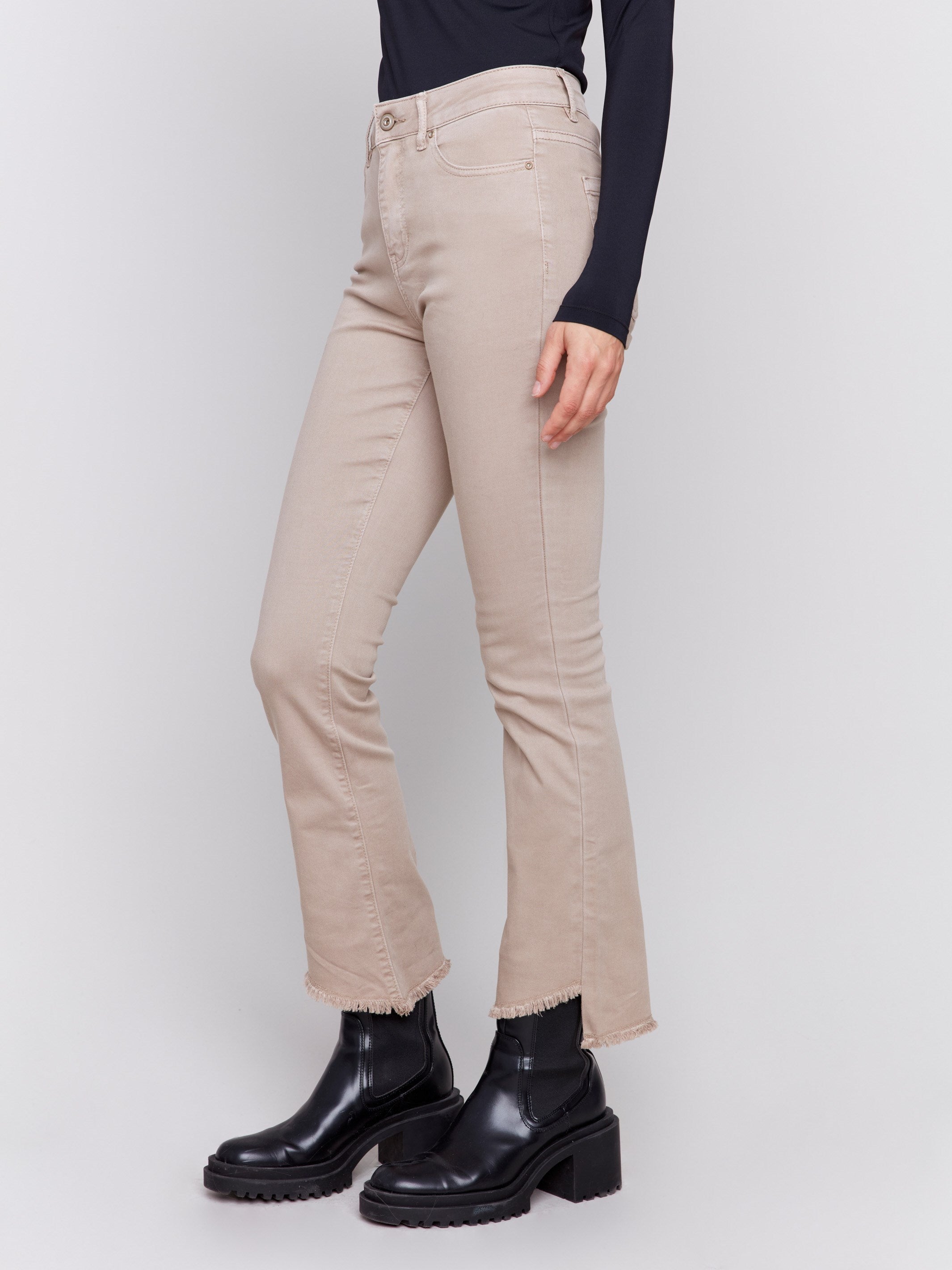 Almond beige bootcut twill pants with an asymmetrical fringe hem and mid-rise waist by Charlie B.