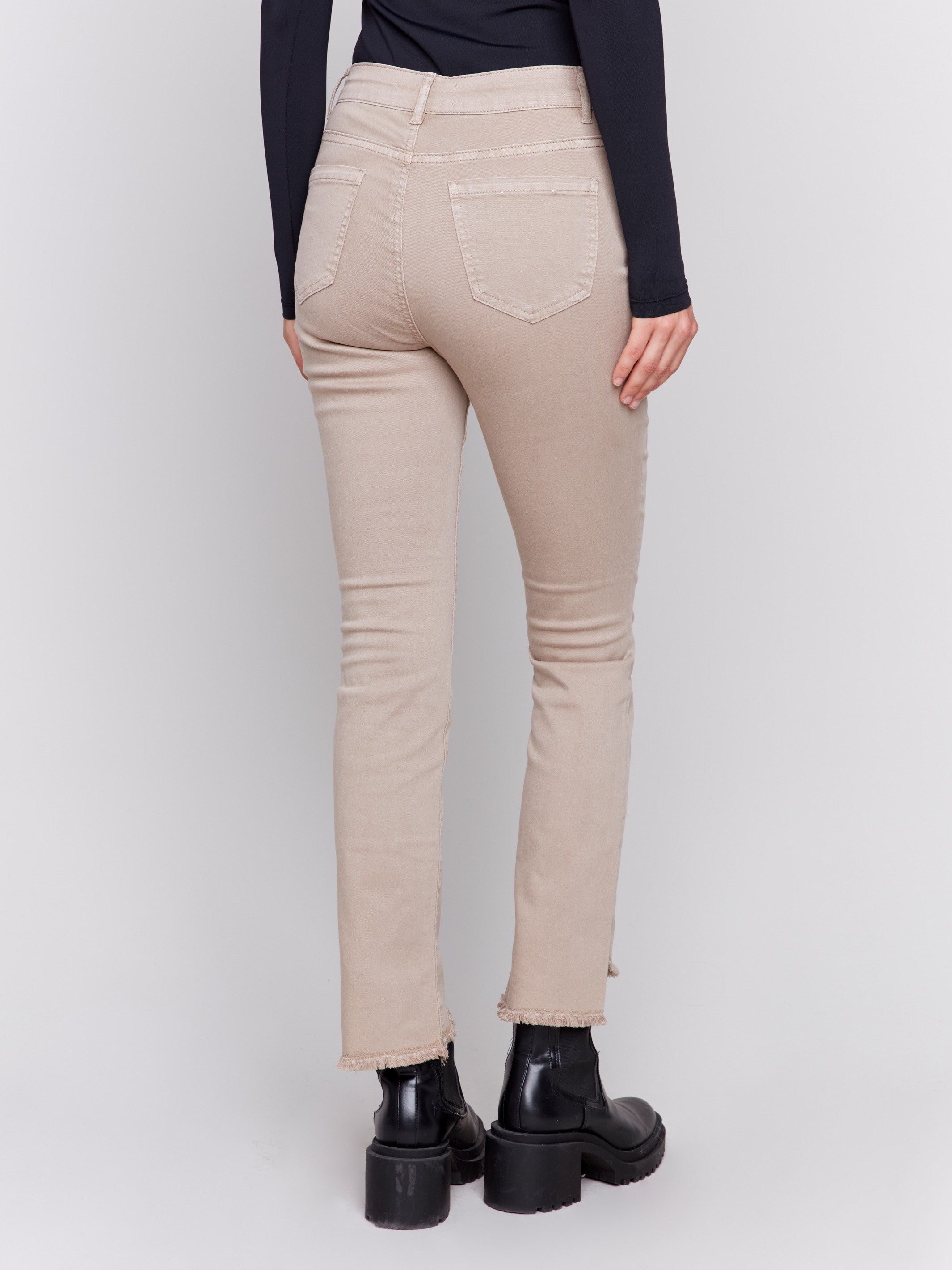 Almond beige bootcut twill pants with an asymmetrical fringe hem and mid-rise waist by Charlie B.