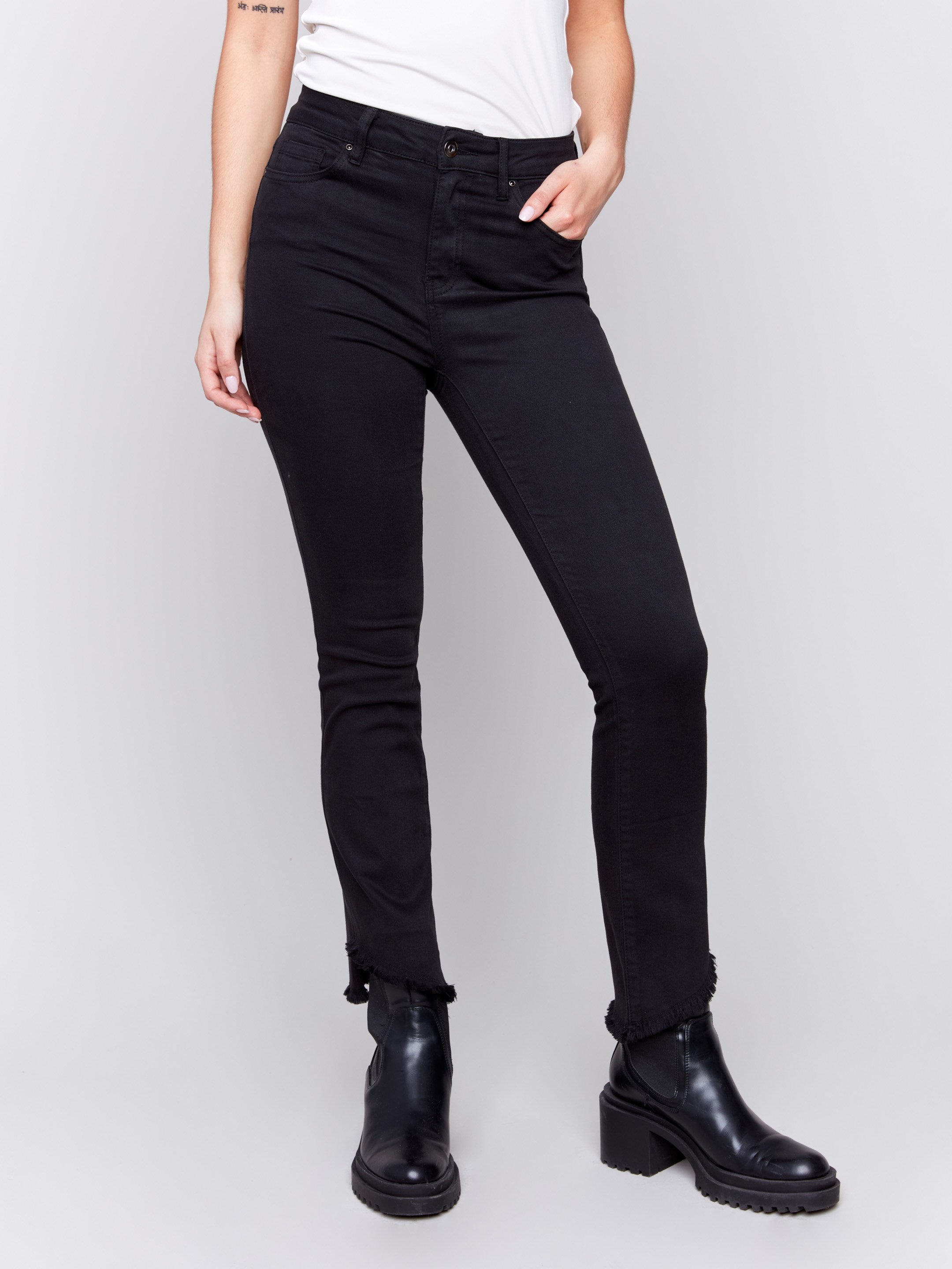 Black bootcut twill pants with an asymmetrical fringe hem and mid-rise waist by Charlie B.