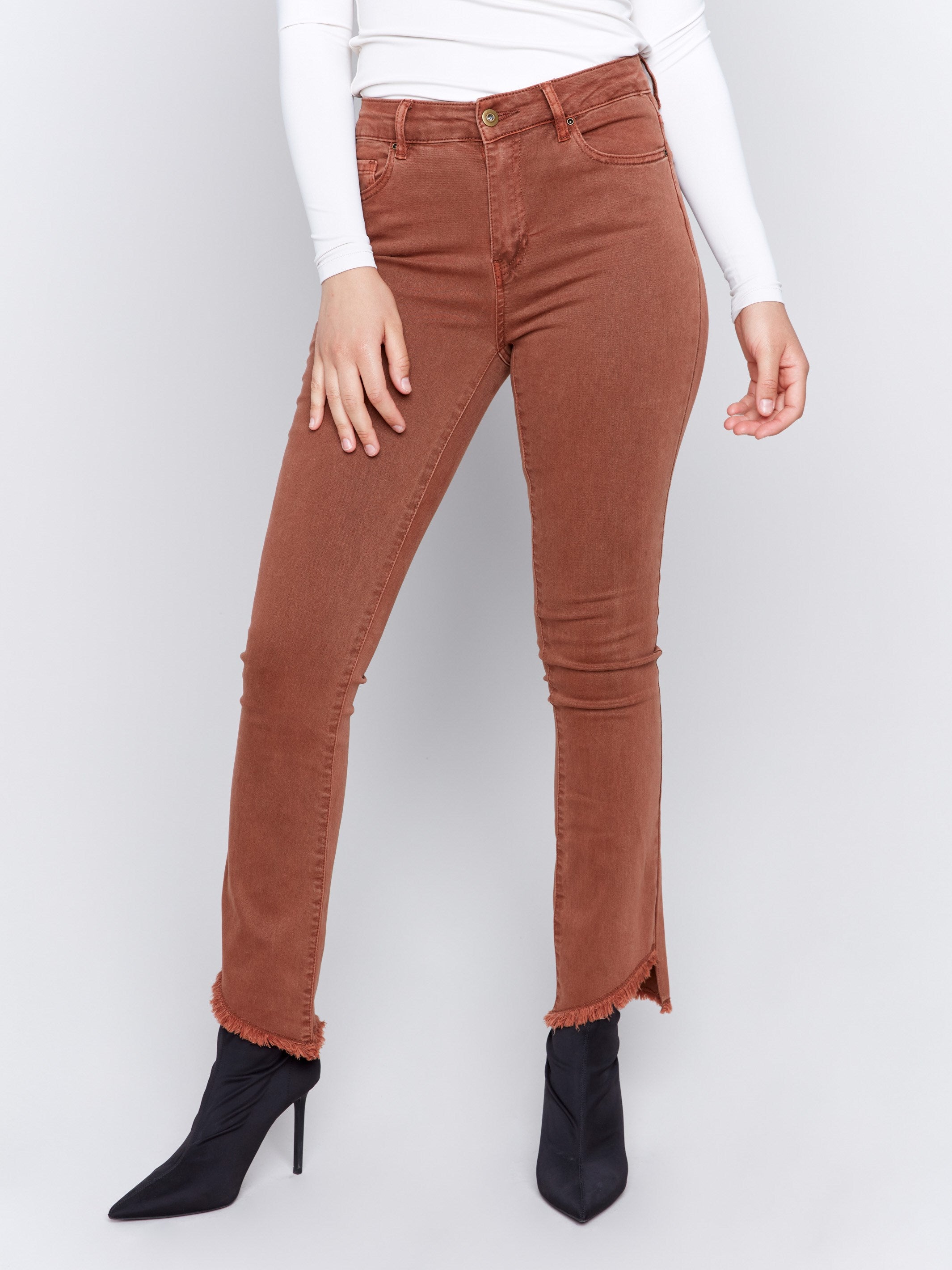 Terracotta red bootcut twill pants with an asymmetrical fringe hem and mid-rise waist by Charlie B.