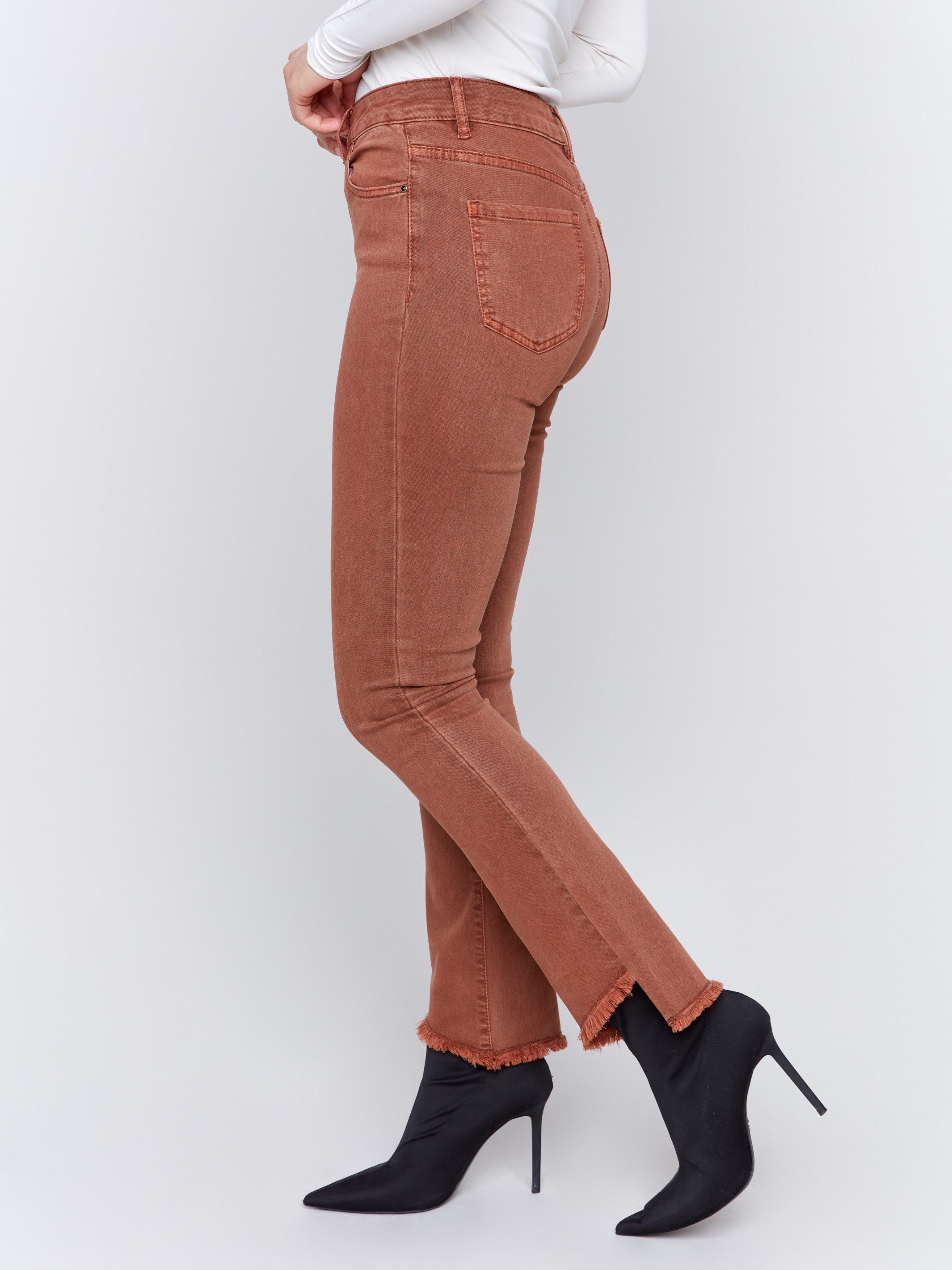 Terracotta red bootcut twill pants with an asymmetrical fringe hem and mid-rise waist by Charlie B.