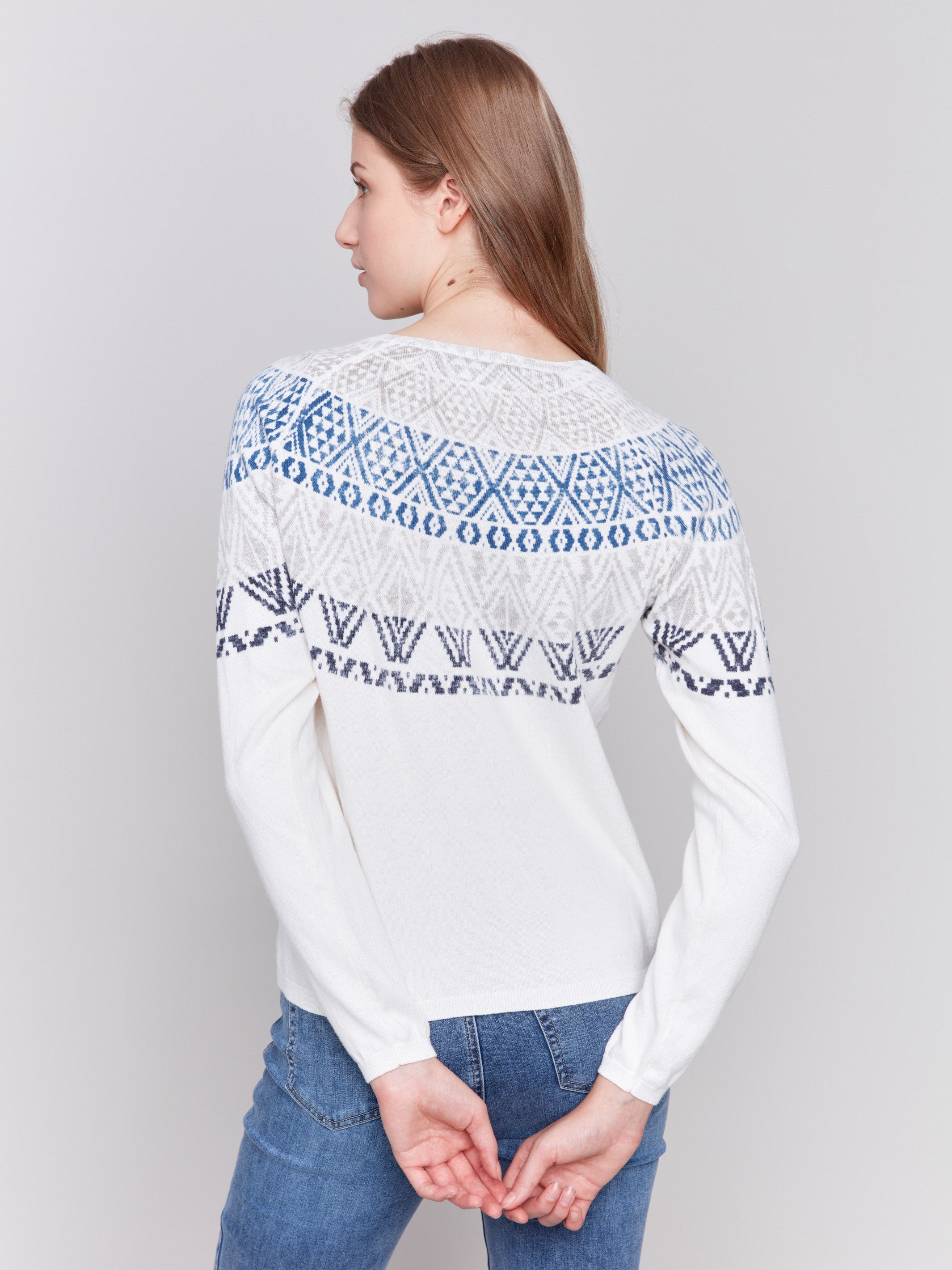 Light ecru ski sweater with geometric patterns across the chest and shoulders, featuring long sleeves and a crew neckline by Charlie B.