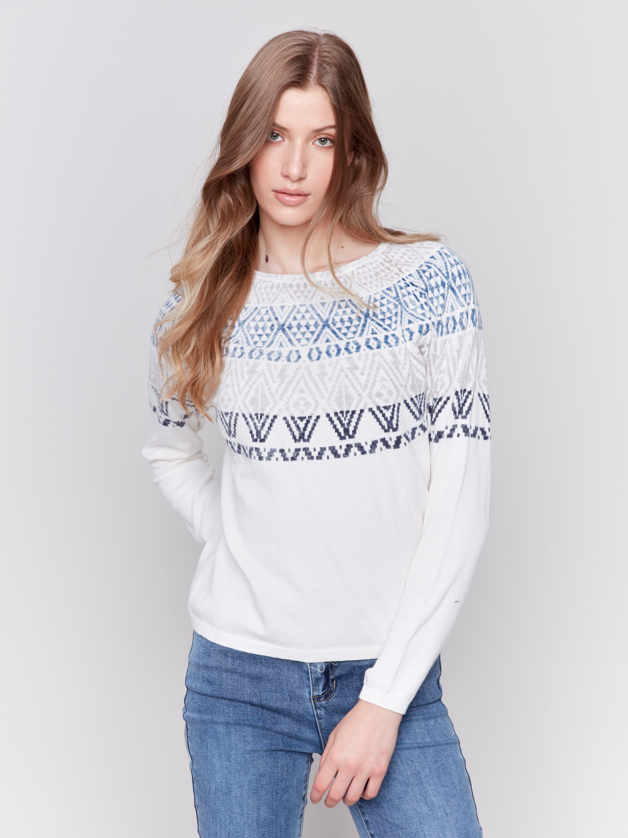 Light ecru ski sweater with geometric patterns across the chest and shoulders, featuring long sleeves and a crew neckline by Charlie B.