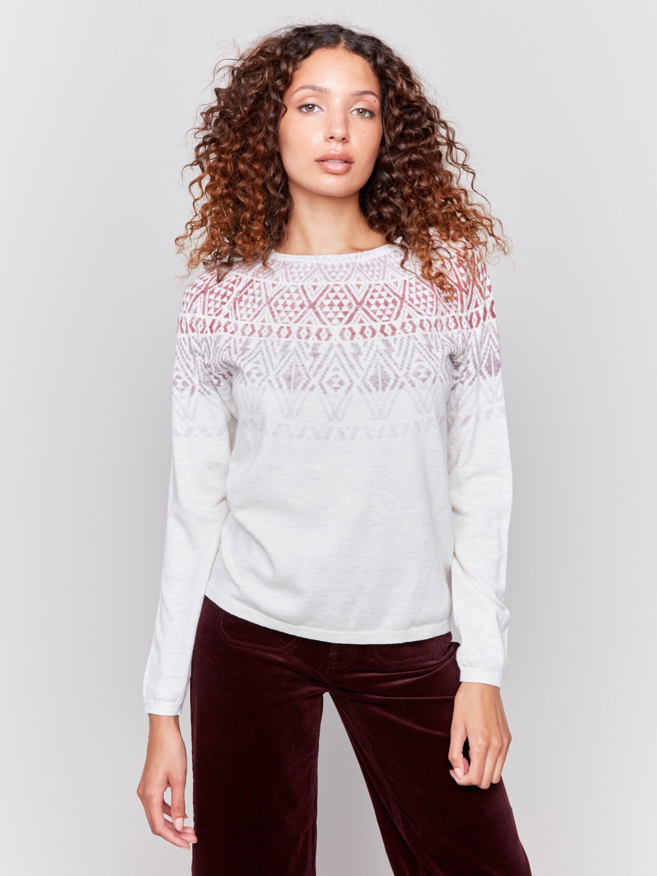 Light grey ski sweater with geometric patterns across the chest and shoulders, featuring long sleeves and a crew neckline by Charlie B.