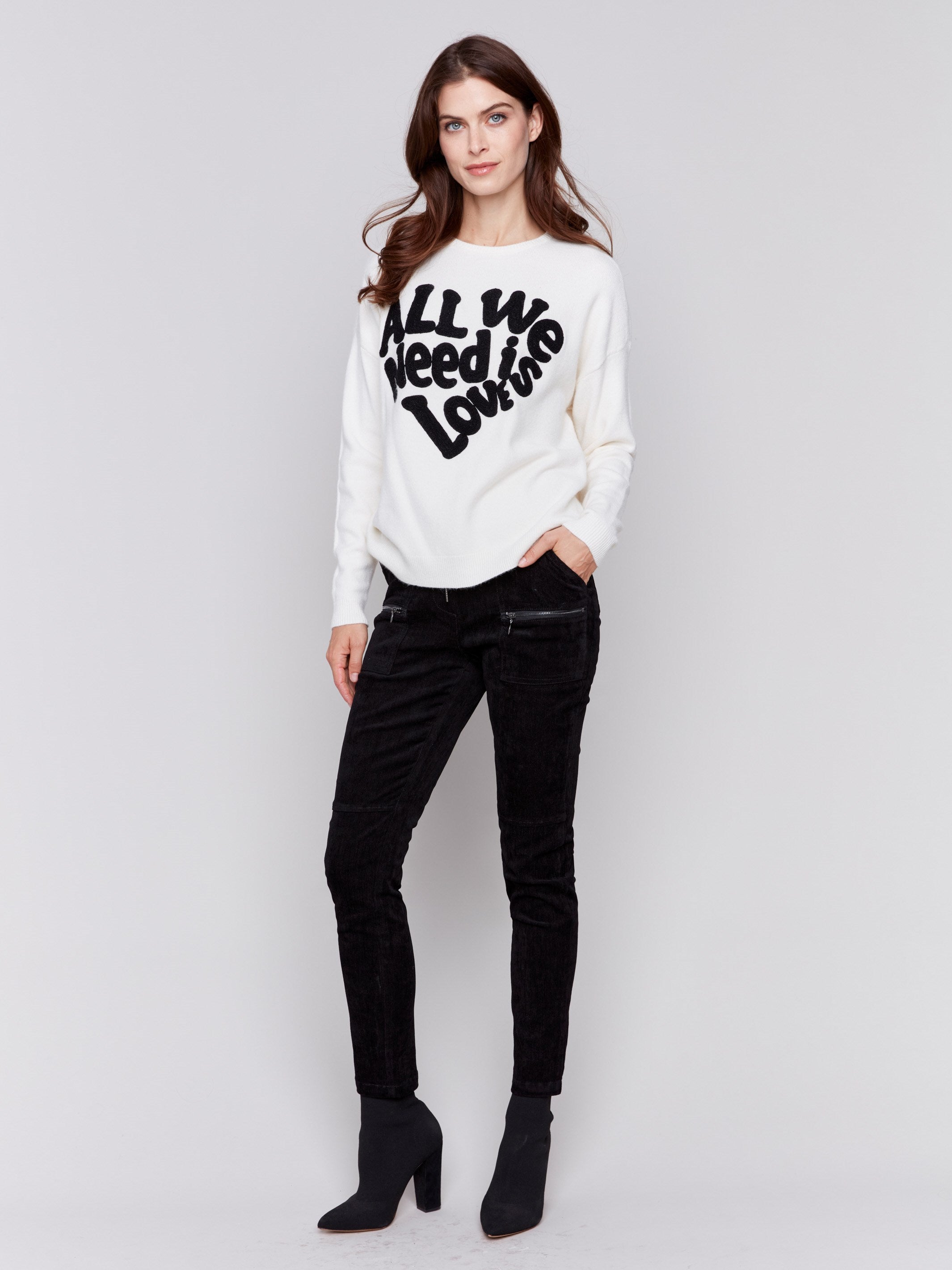 Ecru white crew neck sweater with black 'All We Need is Love' embroidery, featuring a drop shoulder design and long sleeves by Charlie B.