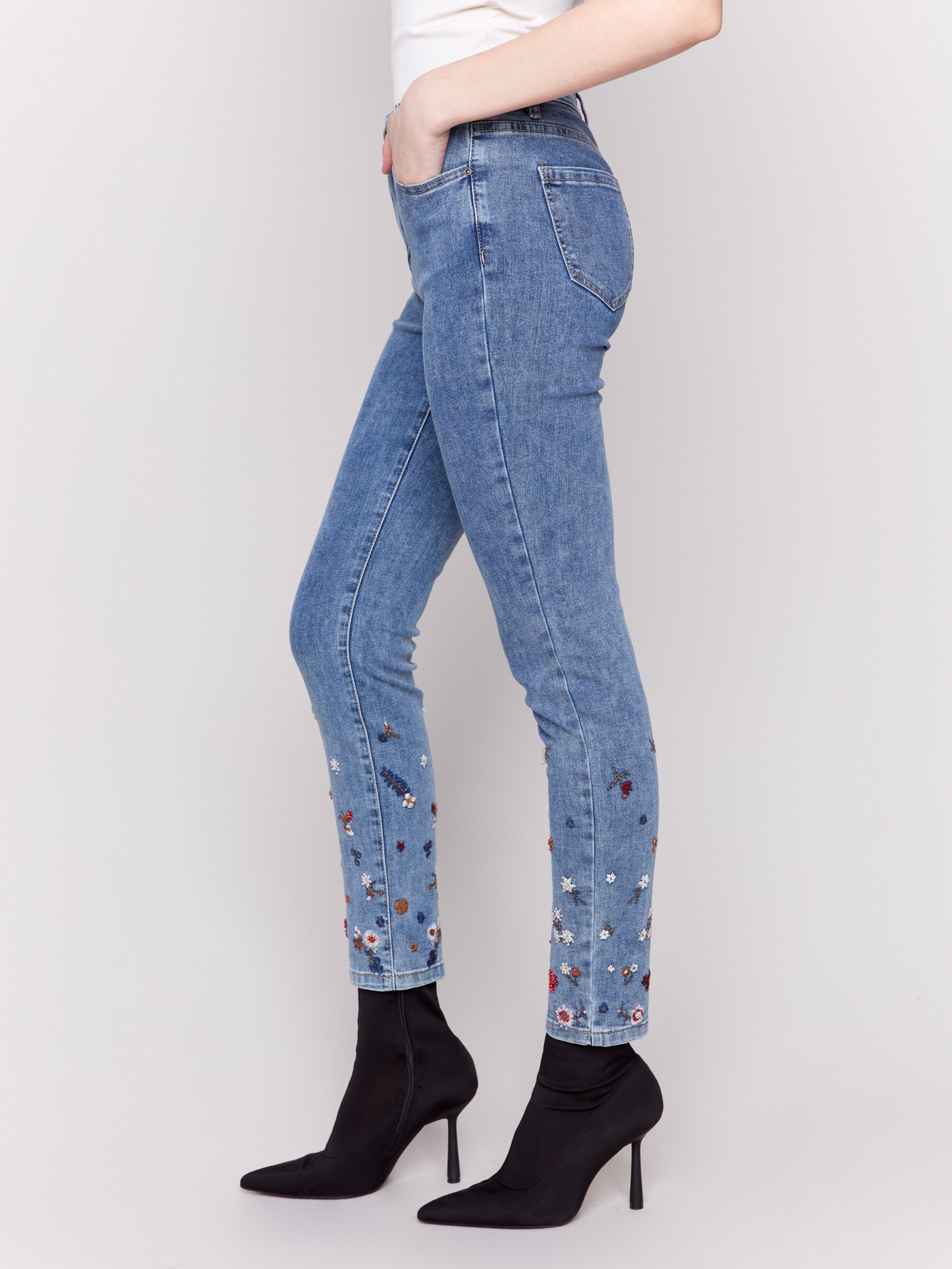 Medium blue slim fit jeans featuring floral embroidery and bead details on the lower legs, with a classic five-pocket design by Charlie B.