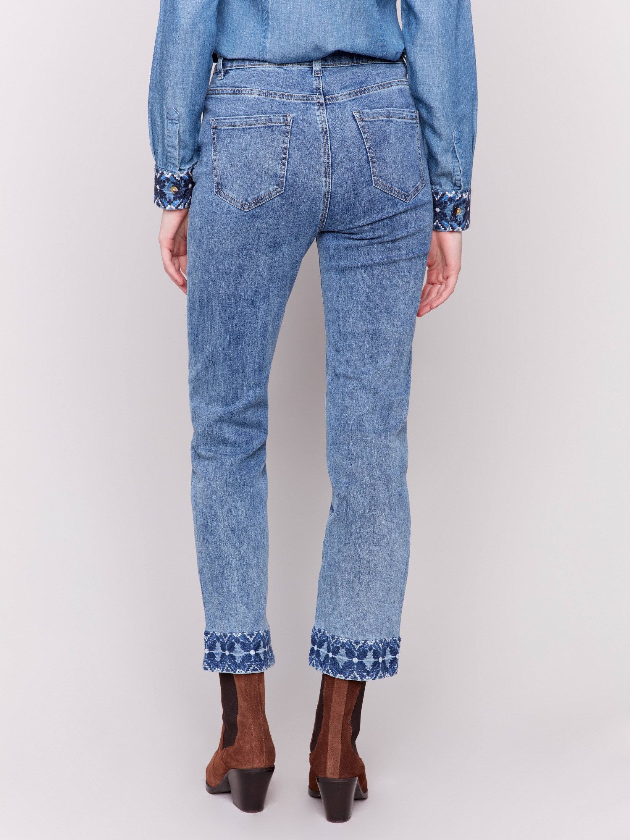 Medium blue straight leg jeans with intricate embroidered cuffs and a classic five-pocket design by Charlie B.