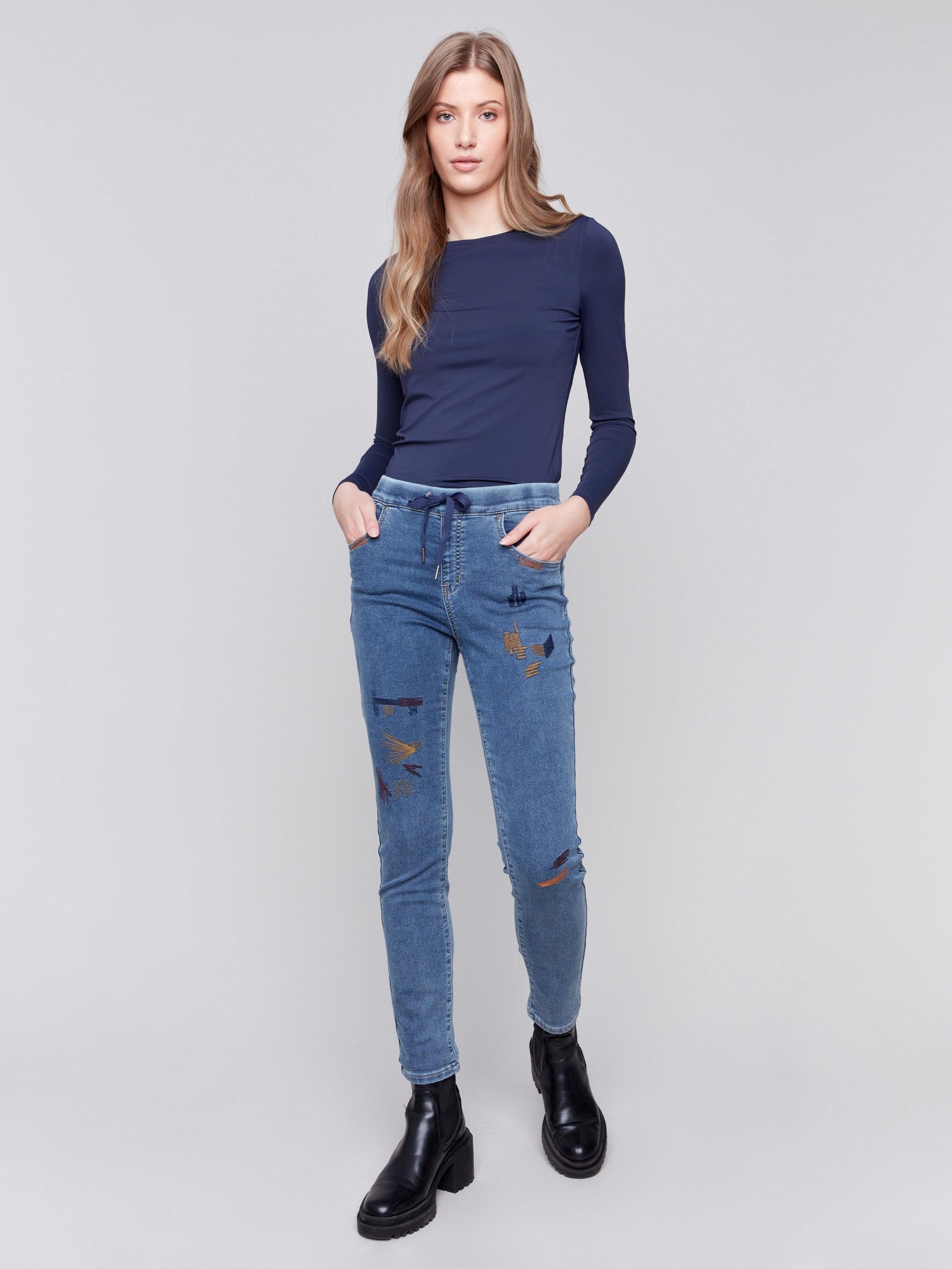 Medium blue embroidered knit denim jogger pants with elasticized waistband and slim leg by Charlie B.