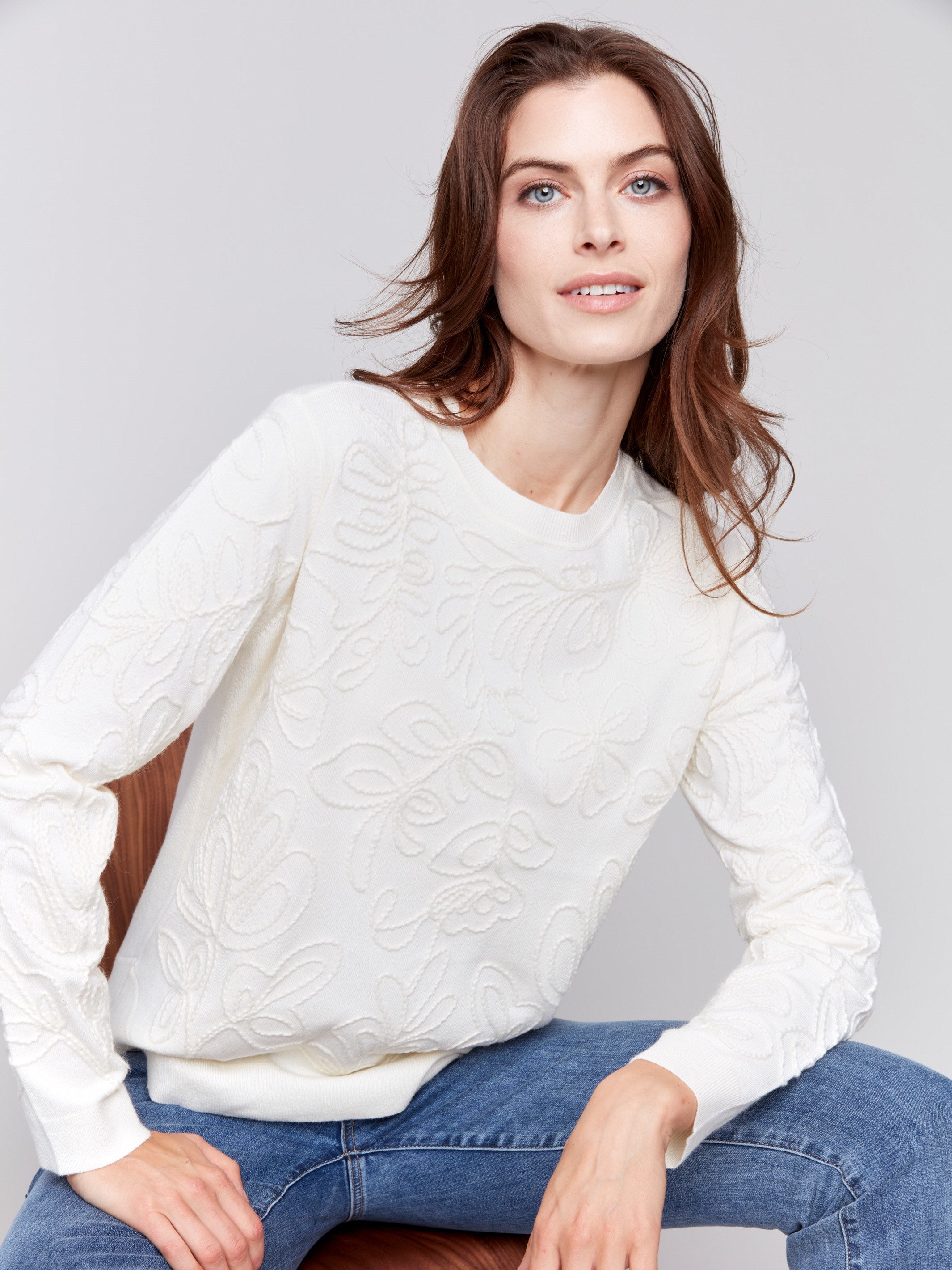 White sweater with floral embroidery, long sleeves, and a round neckline by Charlie B.