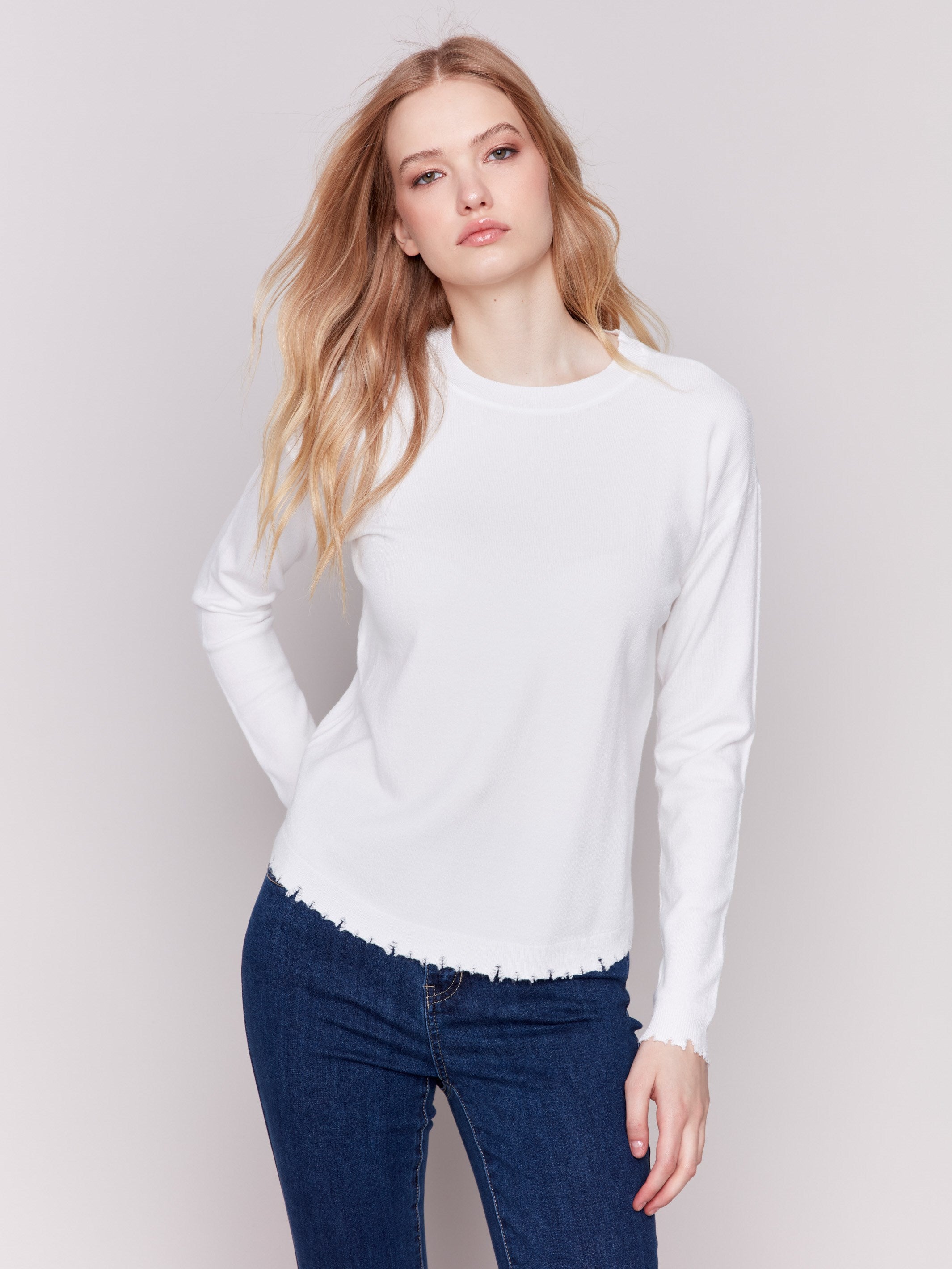 Cream white long-sleeve sweater with a crew neck and frayed rounded hem by Charlie B.