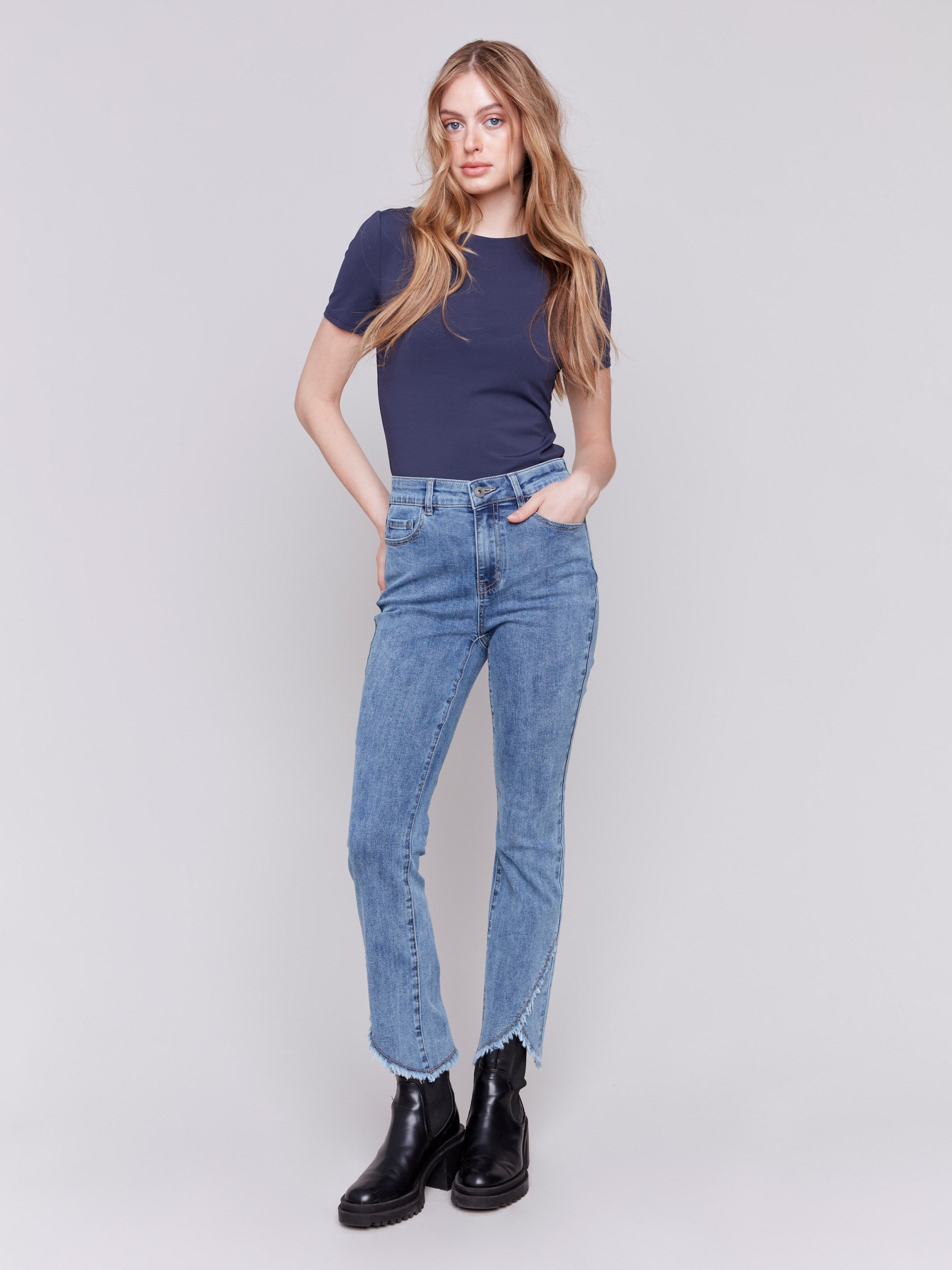 Medium blue denim jeans with a tulip hem and bootcut design by Charlie B. Featuring a mid-rise and frayed hem details.