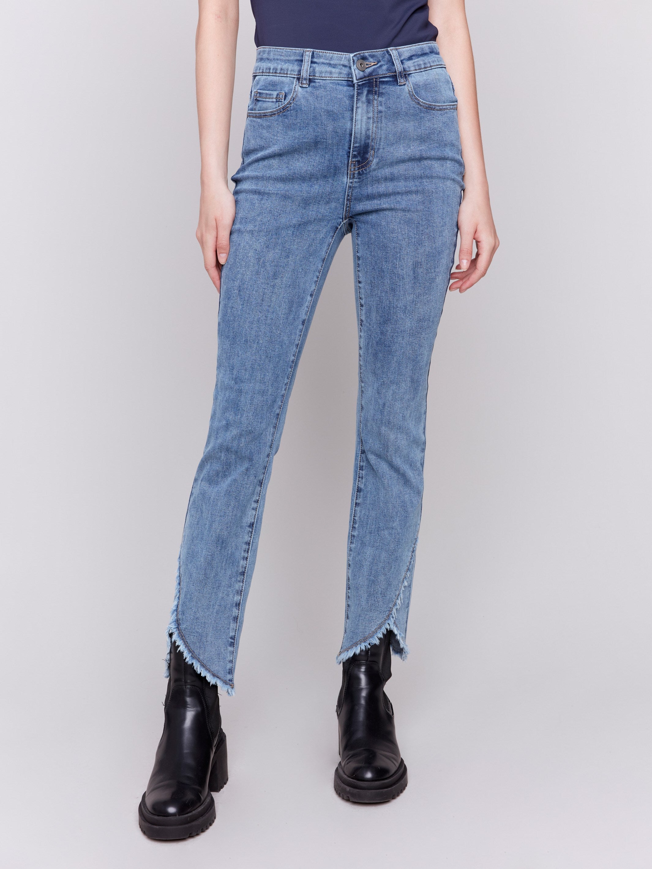 Medium blue denim jeans with a tulip hem and bootcut design by Charlie B. Featuring a mid-rise and frayed hem details.