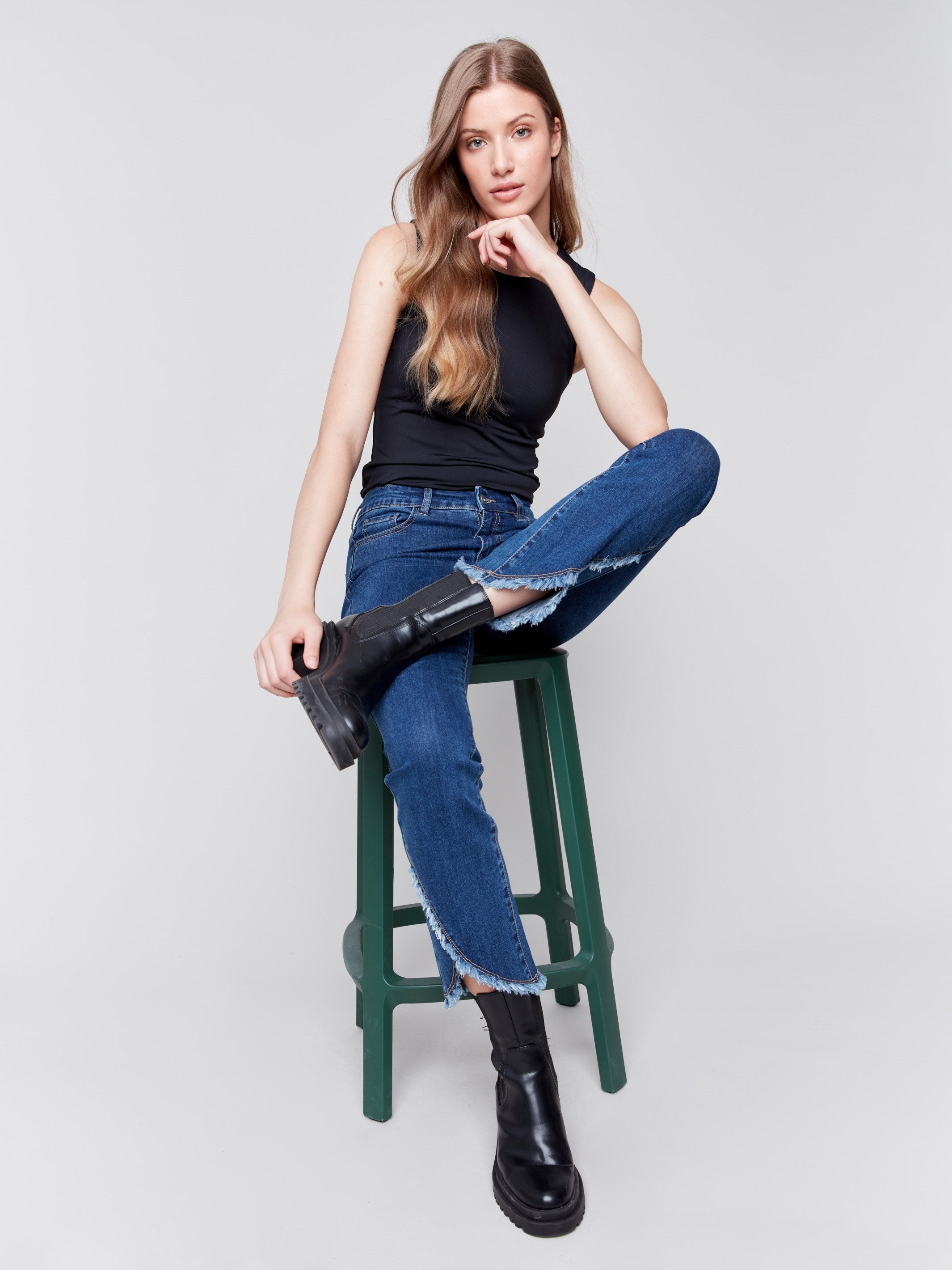 Indigo blue denim jeans with a tulip hem and bootcut design by Charlie B. Featuring a mid-rise and frayed hem details.