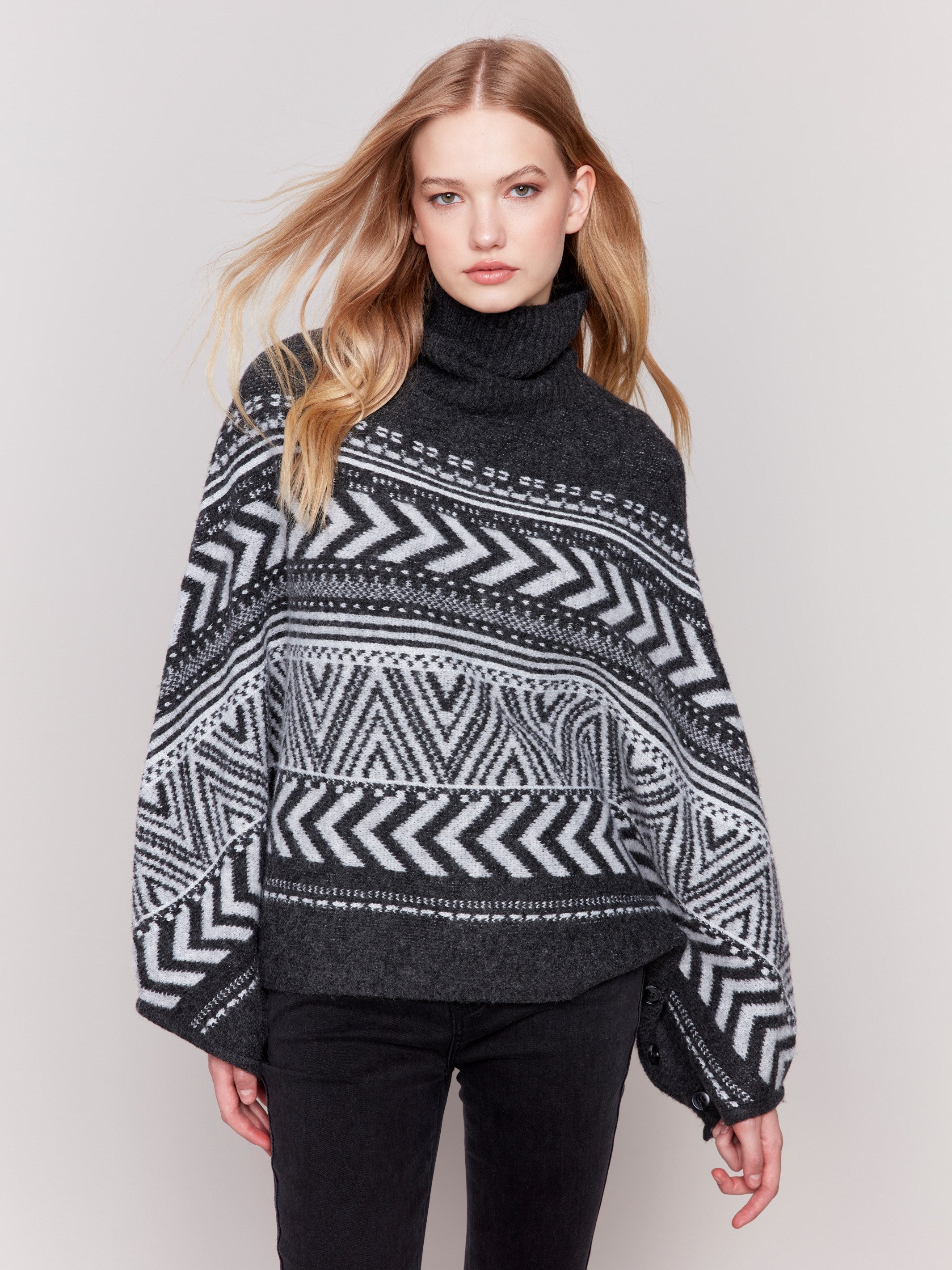 Charcoal poncho with a geometric jacquard pattern, featuring a cozy cowl neck and buttoned sleeves by Charlie B.