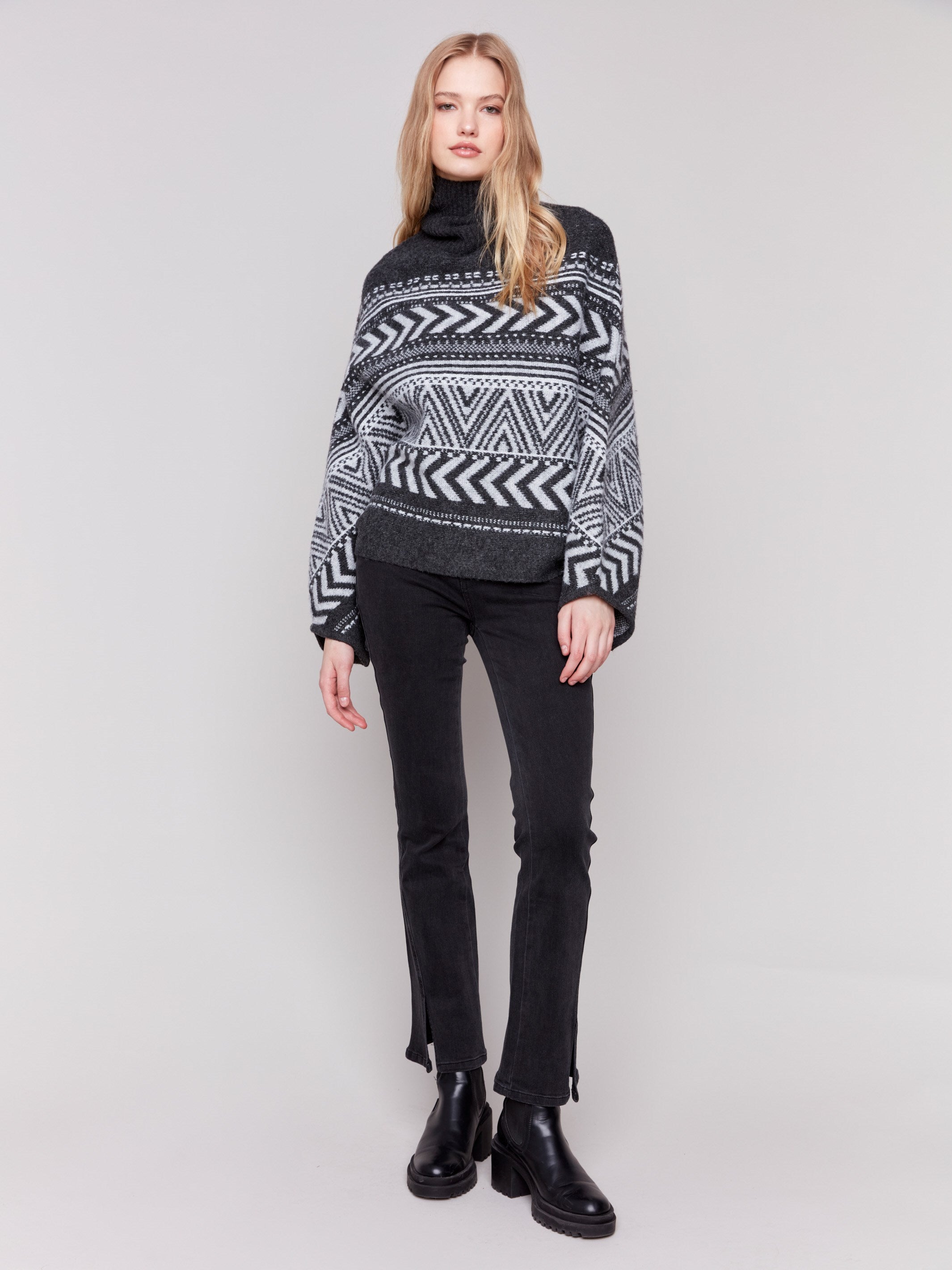 Charcoal poncho with a geometric jacquard pattern, featuring a cozy cowl neck and buttoned sleeves by Charlie B.