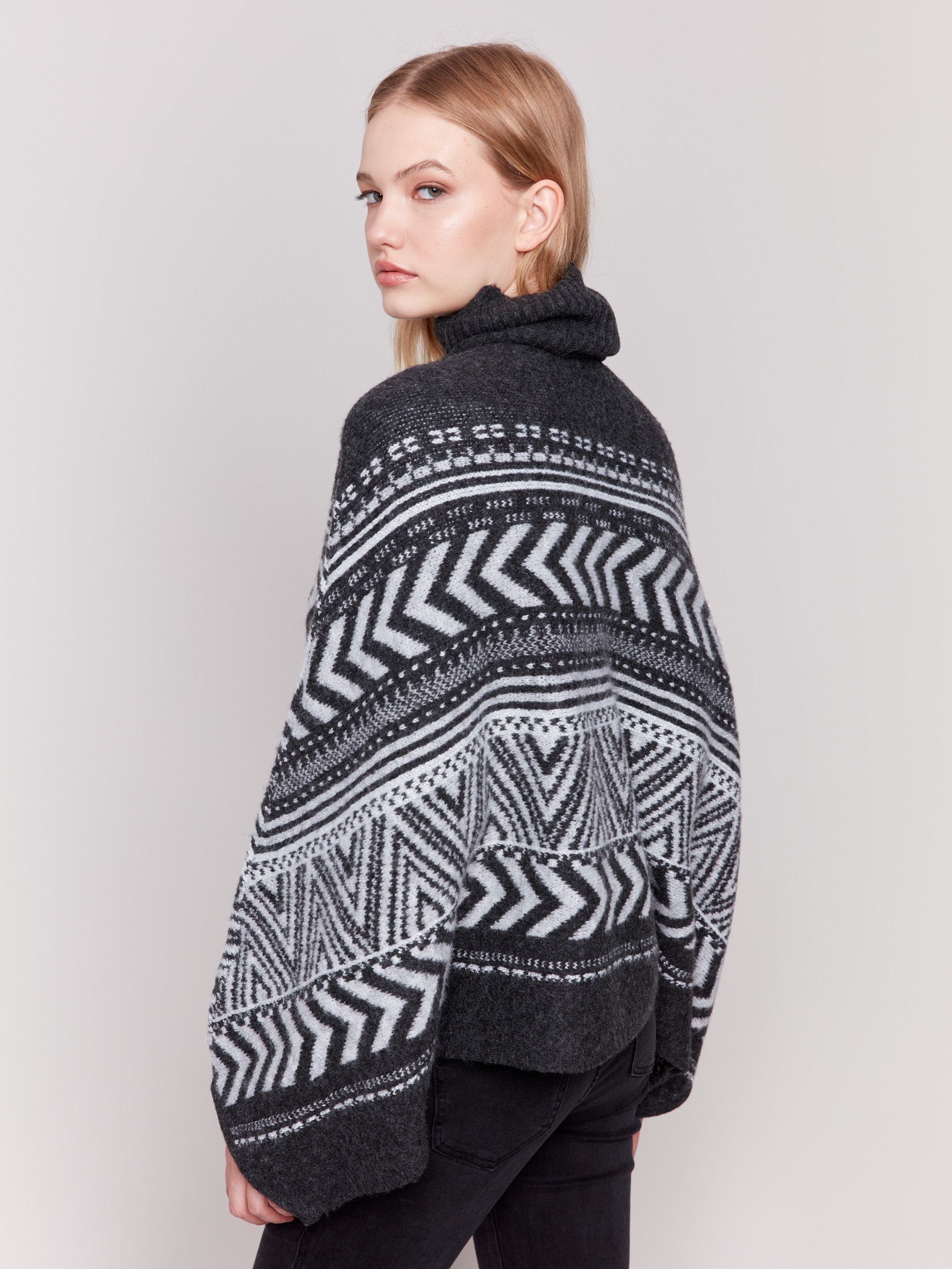 Charcoal poncho with a geometric jacquard pattern, featuring a cozy cowl neck and buttoned sleeves by Charlie B.