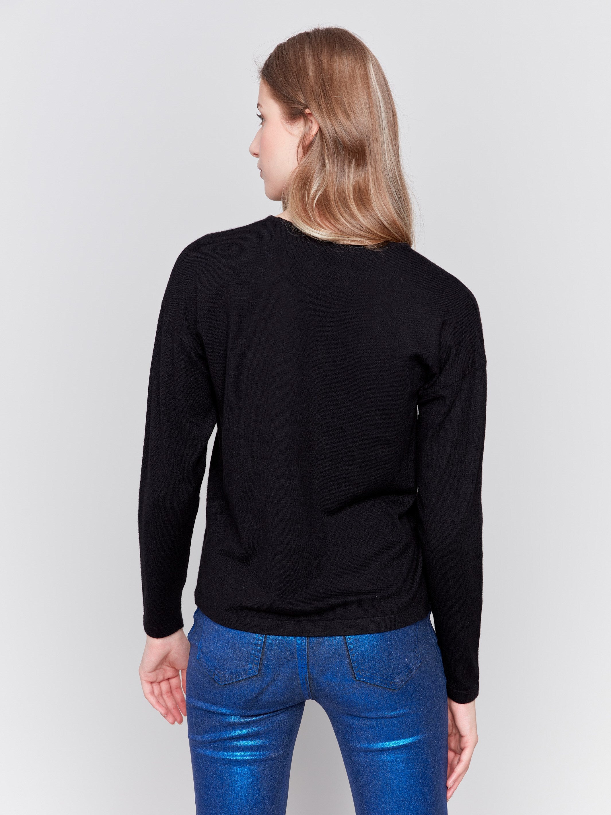 Black v-neck sweater with heart stitch design, featuring long sleeves and a relaxed fit by Charlie B.