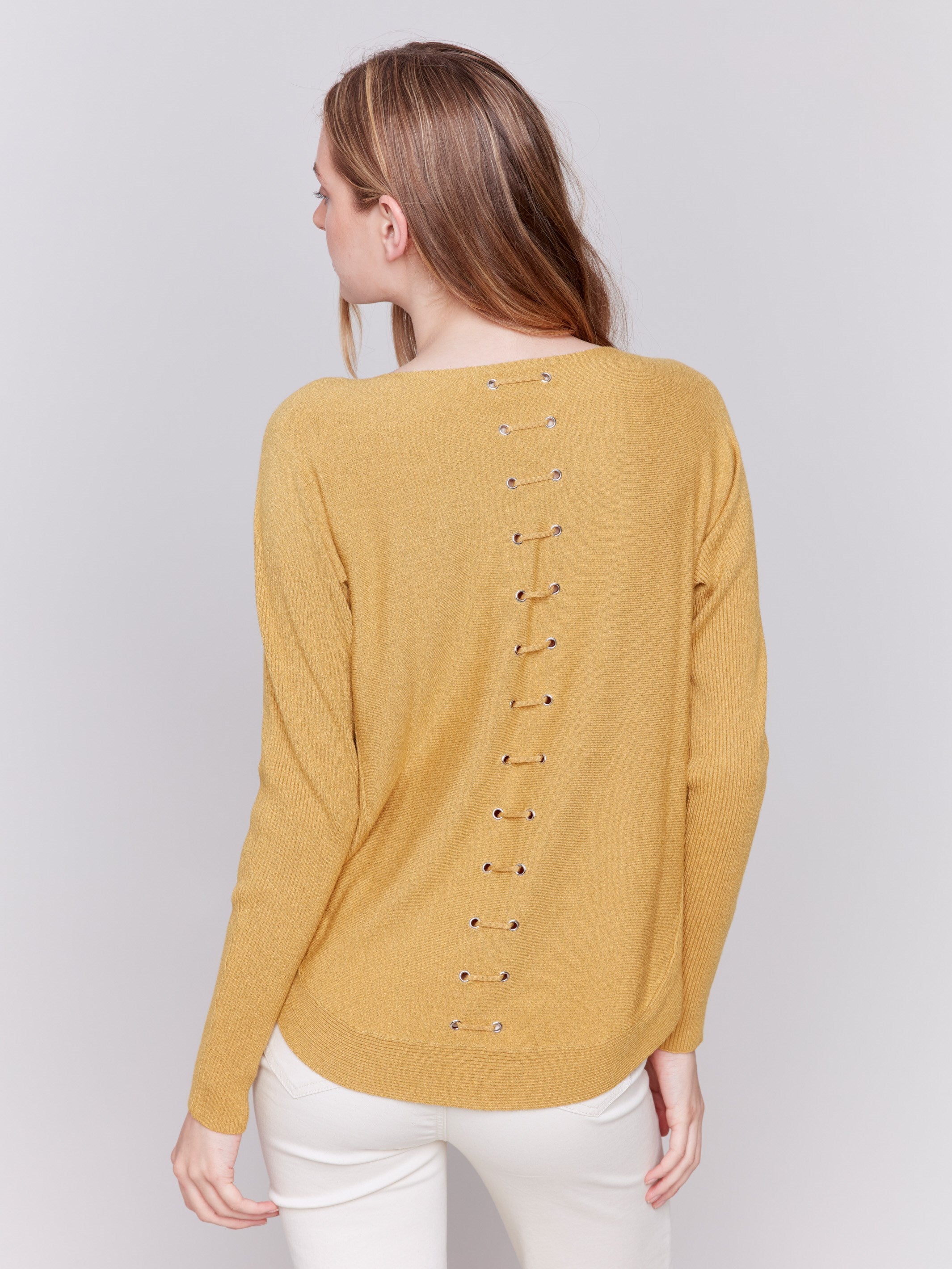 Amber yellow knit sweater with a crew neckline, long ribbed sleeves, and back lace-up eyelet details by Charlie B.