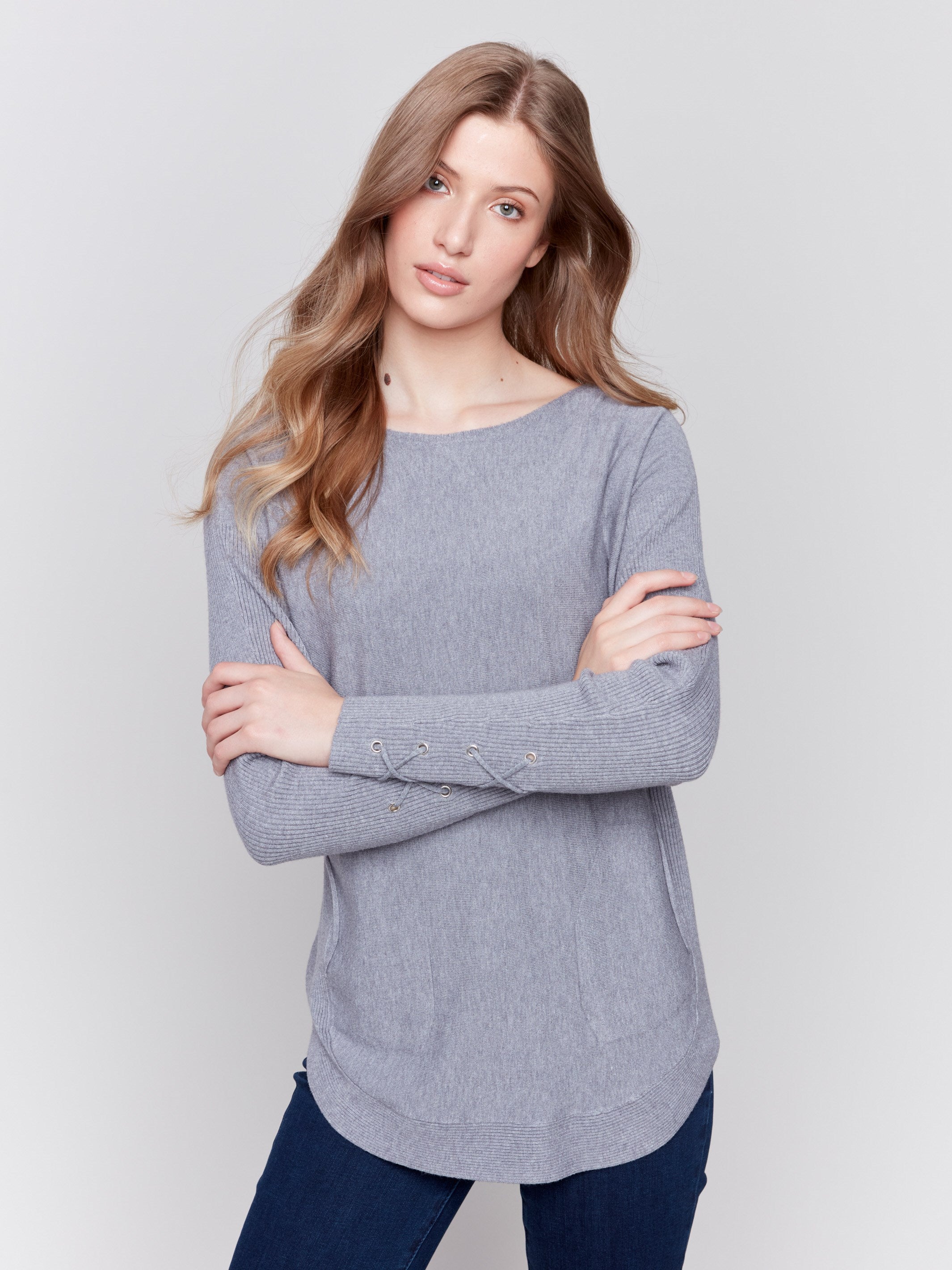 Grey long-sleeved knit sweater with lace-up cuffs, rounded hem, and front pockets by Charlie B.