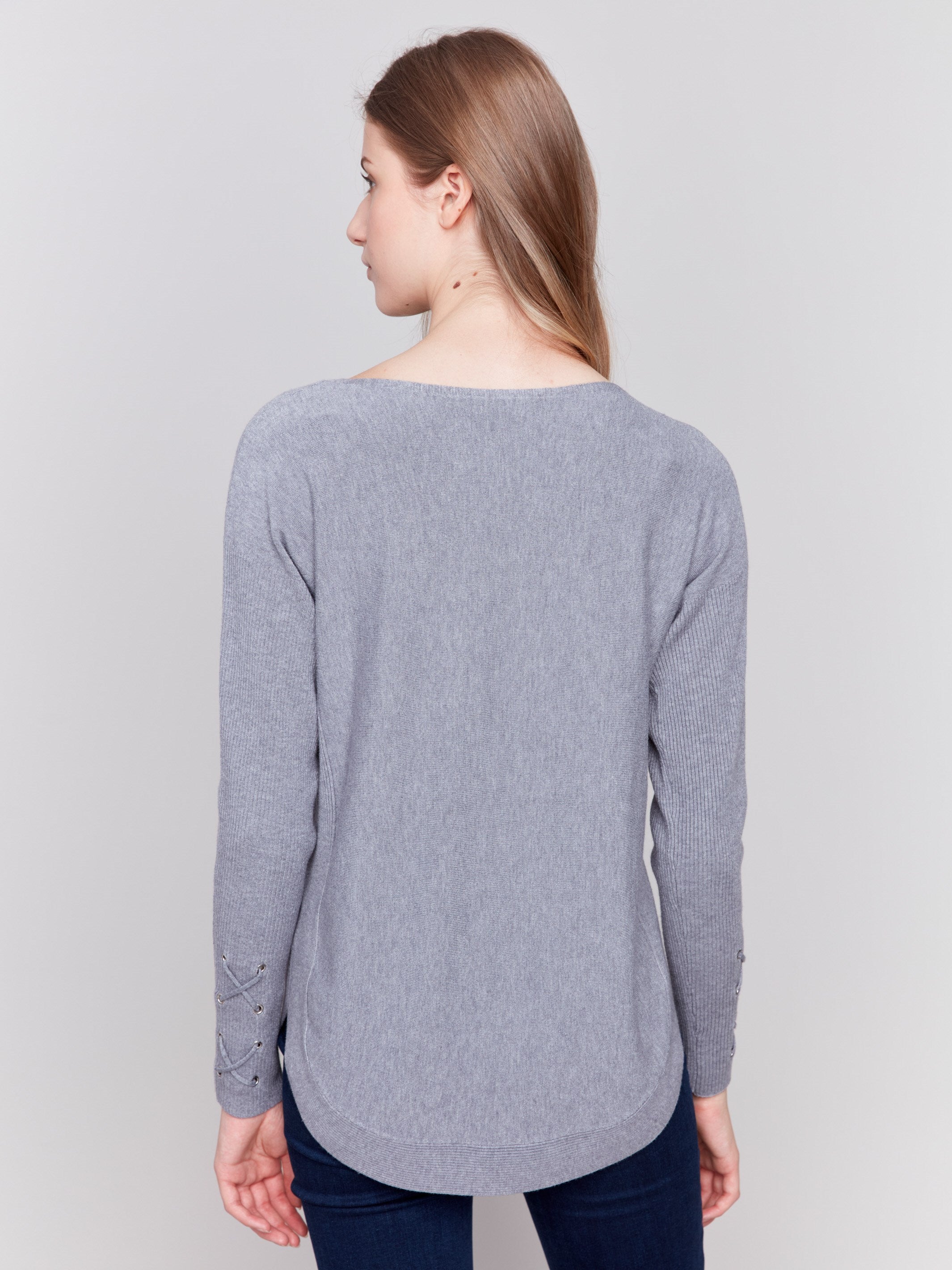 Grey long-sleeved knit sweater with lace-up cuffs, rounded hem, and front pockets by Charlie B.