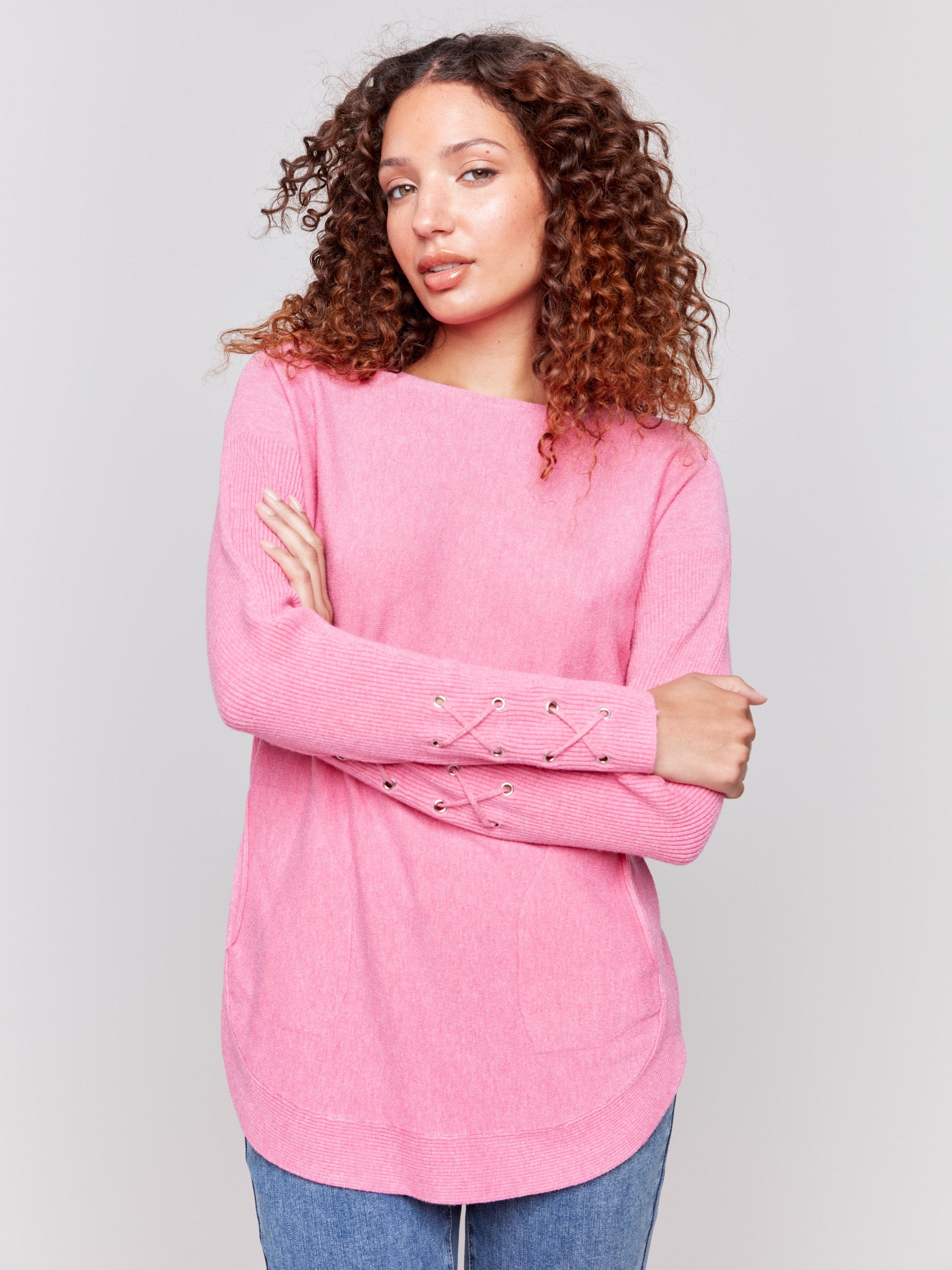 Magenta pink long-sleeved knit sweater with lace-up cuffs, rounded hem, and front pockets by Charlie B.