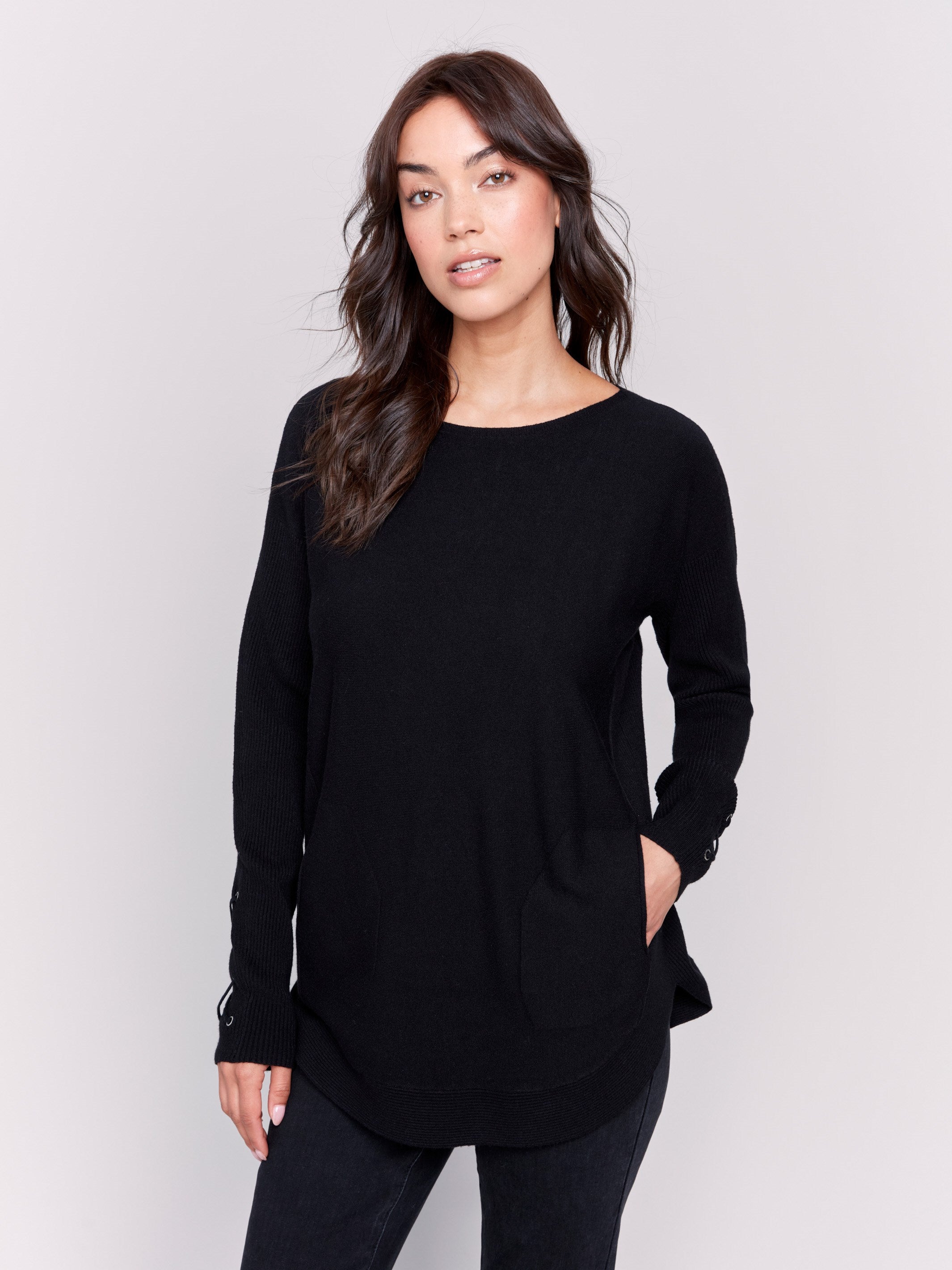 Black long-sleeved knit sweater with lace-up cuffs, rounded hem, and front pockets by Charlie B.