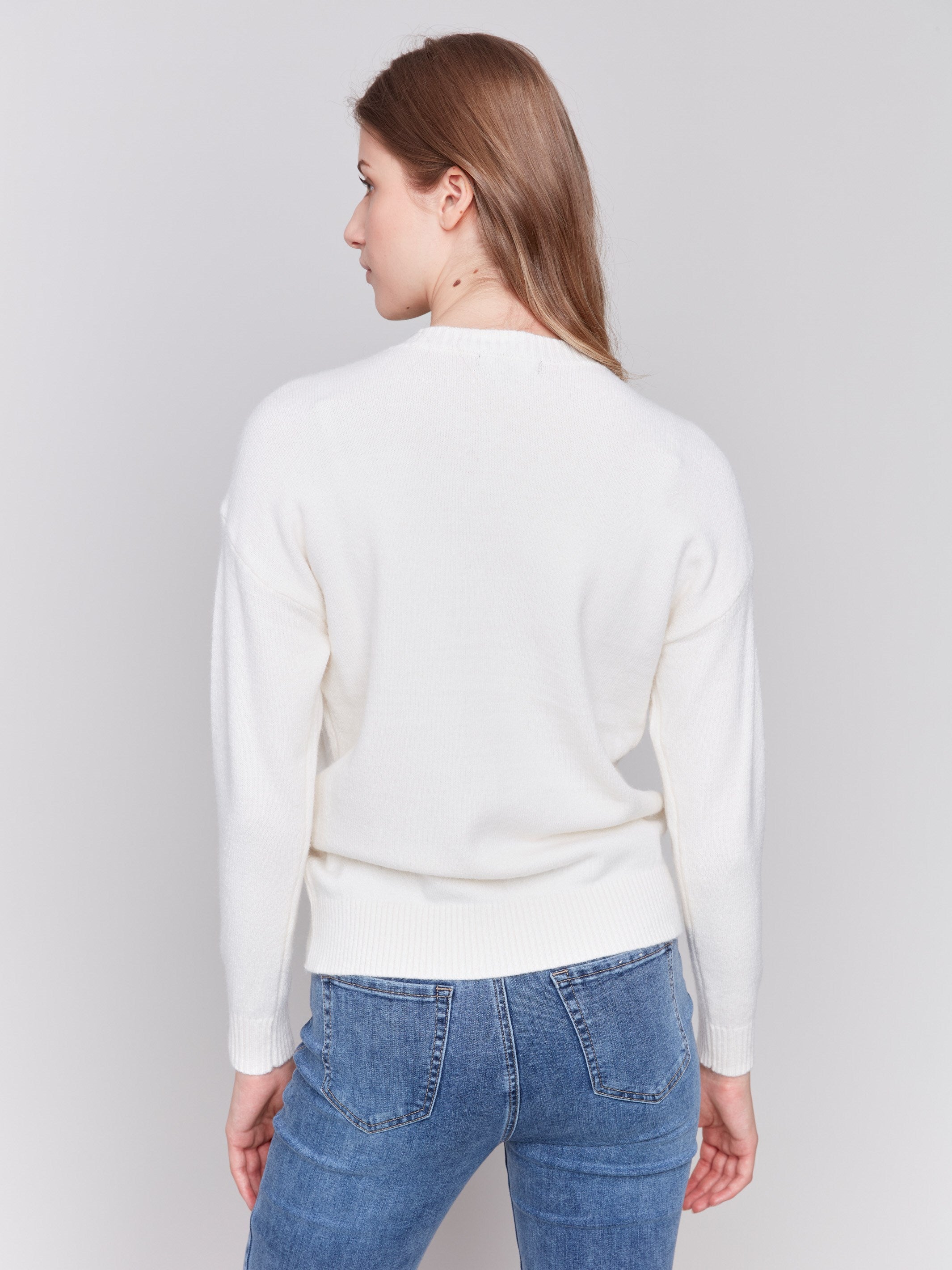 Ecru white sweater featuring a large peace sign graphic on the front with blanket stitch detailing, long sleeves, and crew neckline by Charlie B.