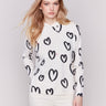 Stylish white hoodie sweater with black heart prints, featuring a drawstring hood and raglan sleeves by Charlie B.