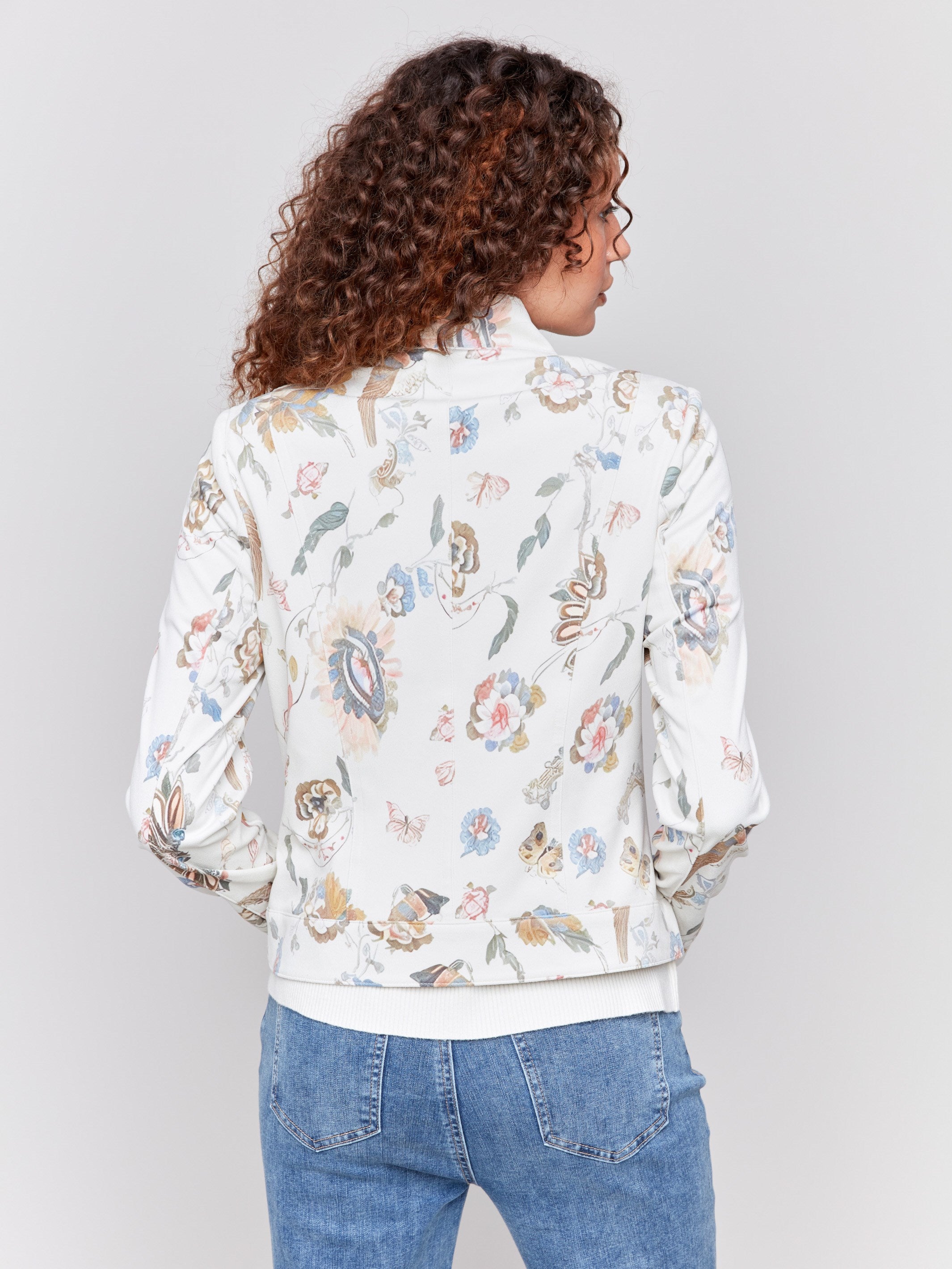 White faux leather jacket with floral print, stand collar, front zipper, and zipper pocket details by Charlie B.