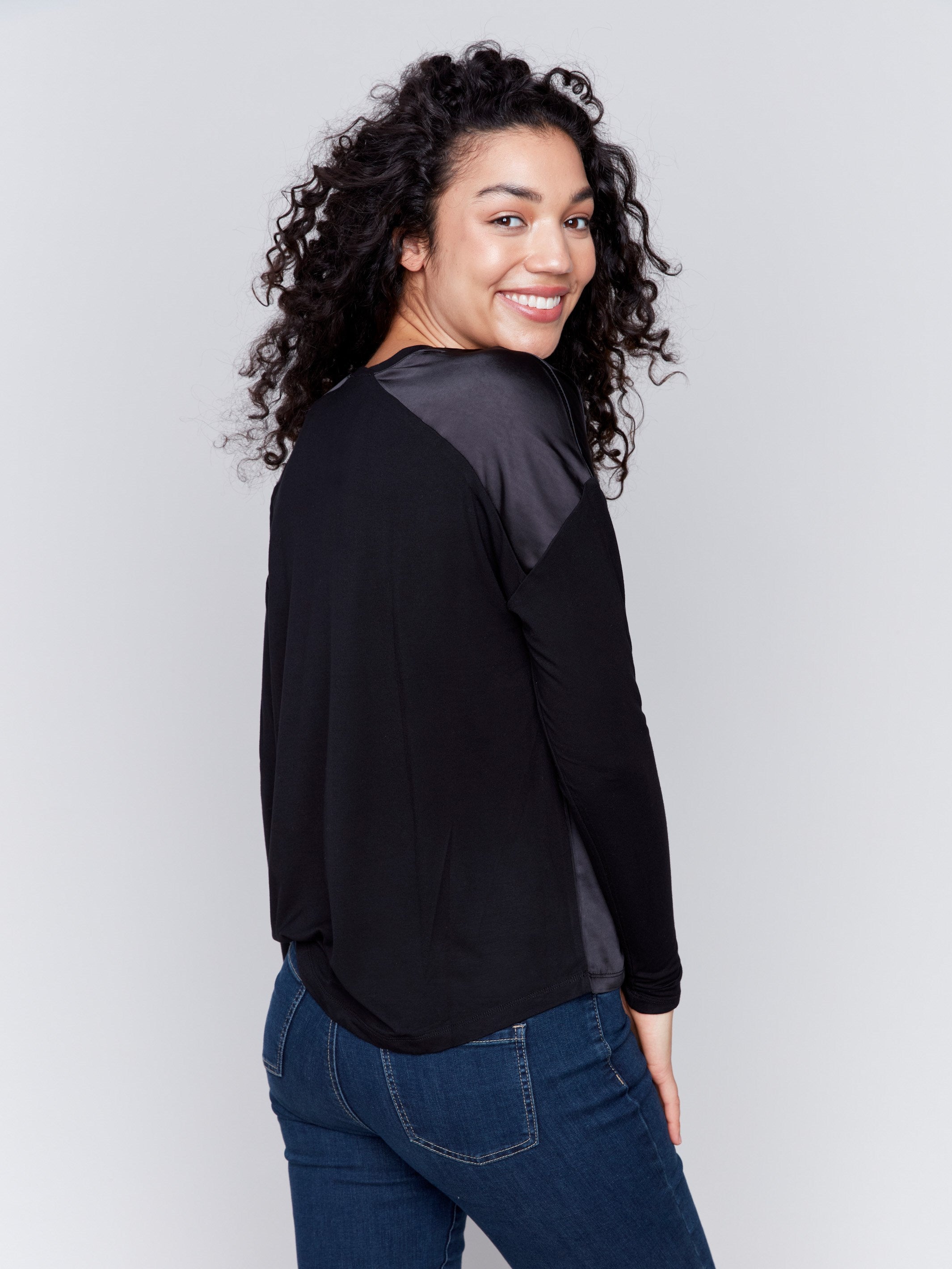 Black satin and jersey top featuring V-neck design and long sleeves by Charlie B.