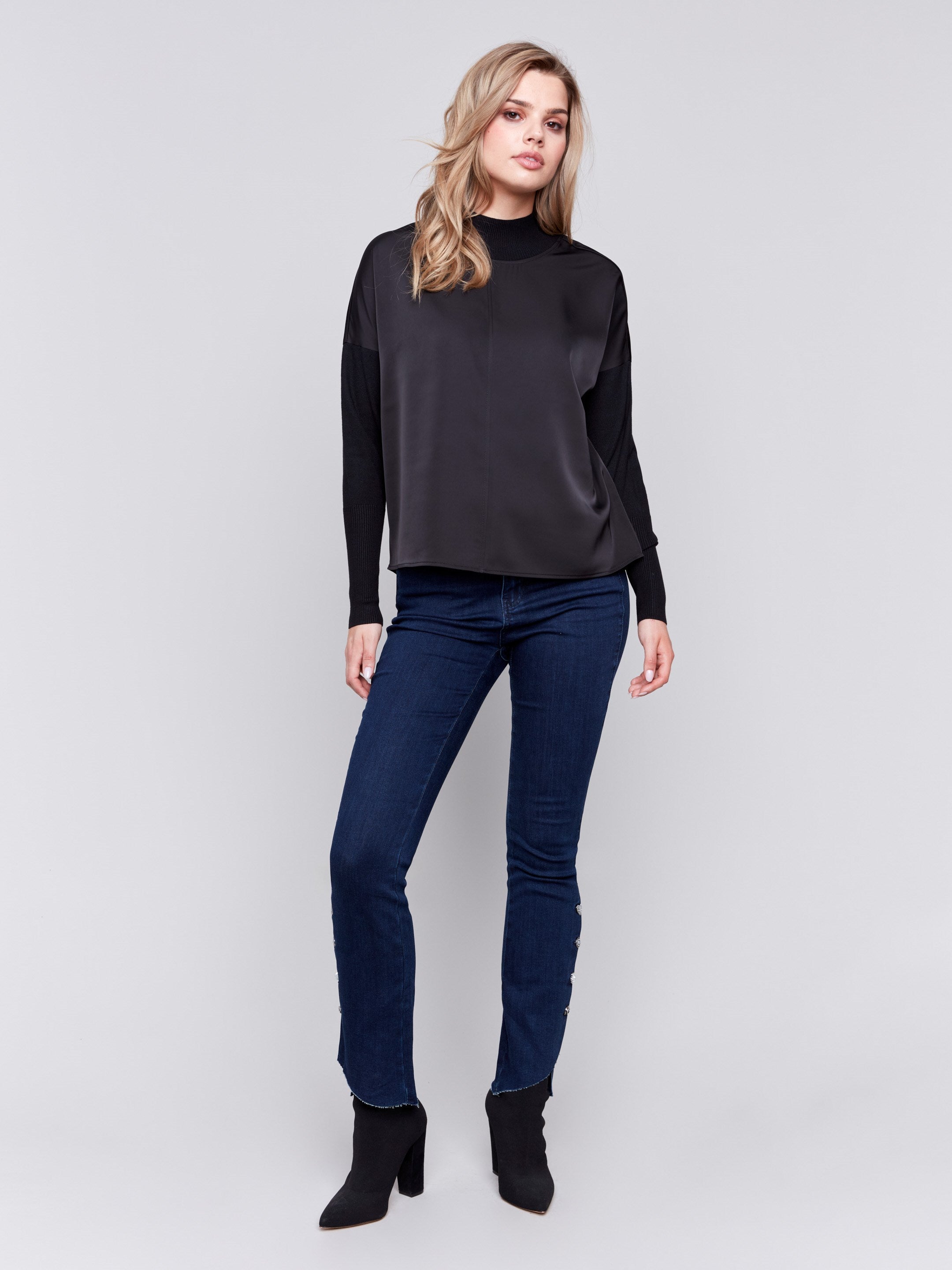 Black satin-knit top with a mock neck and front seam detail, featuring long sleeves and ribbed cuffs by Charlie B.