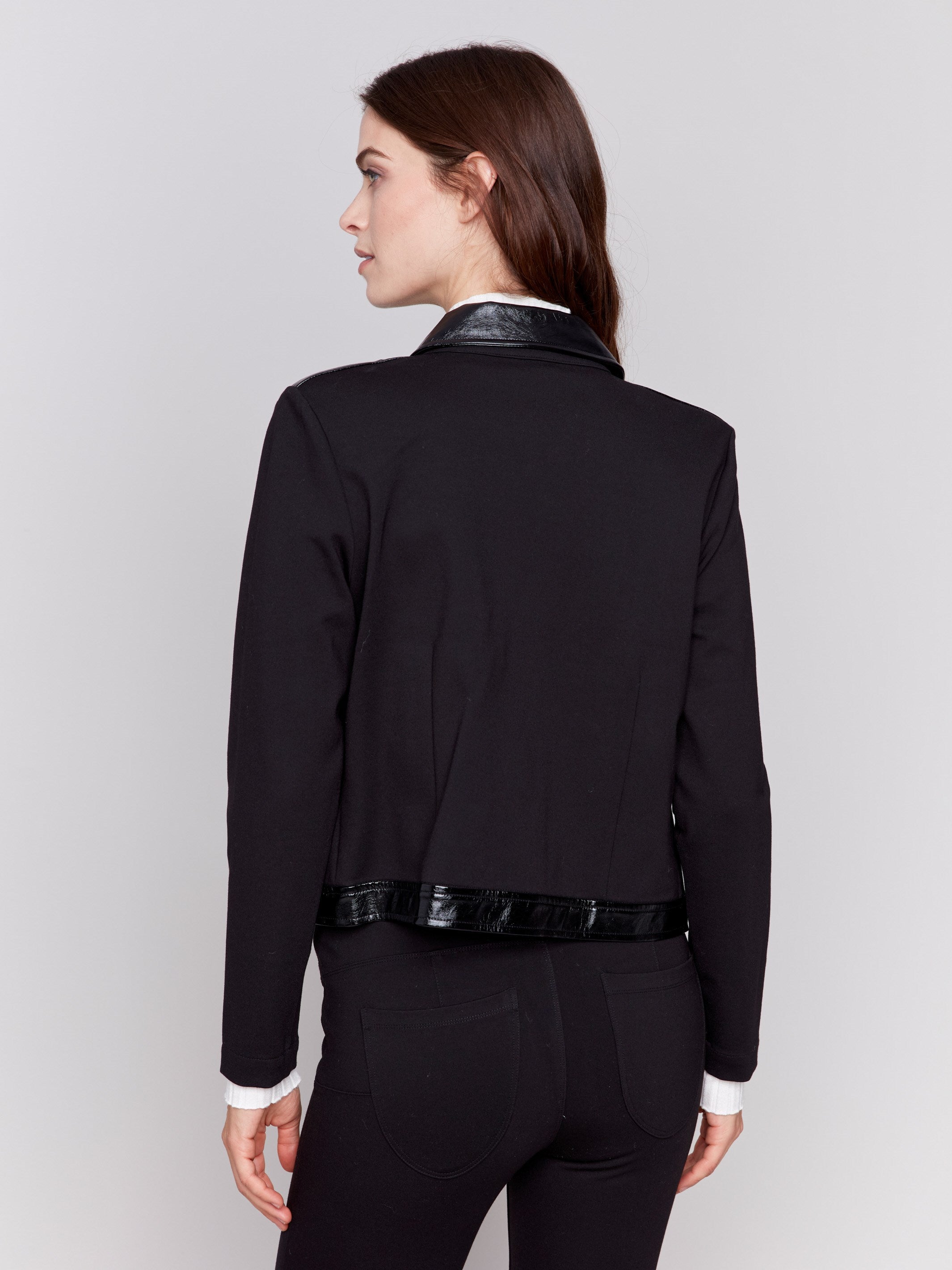 Short black jacket with glossy vinyl trim, featuring front flap pockets and a button closure, by Charlie B.