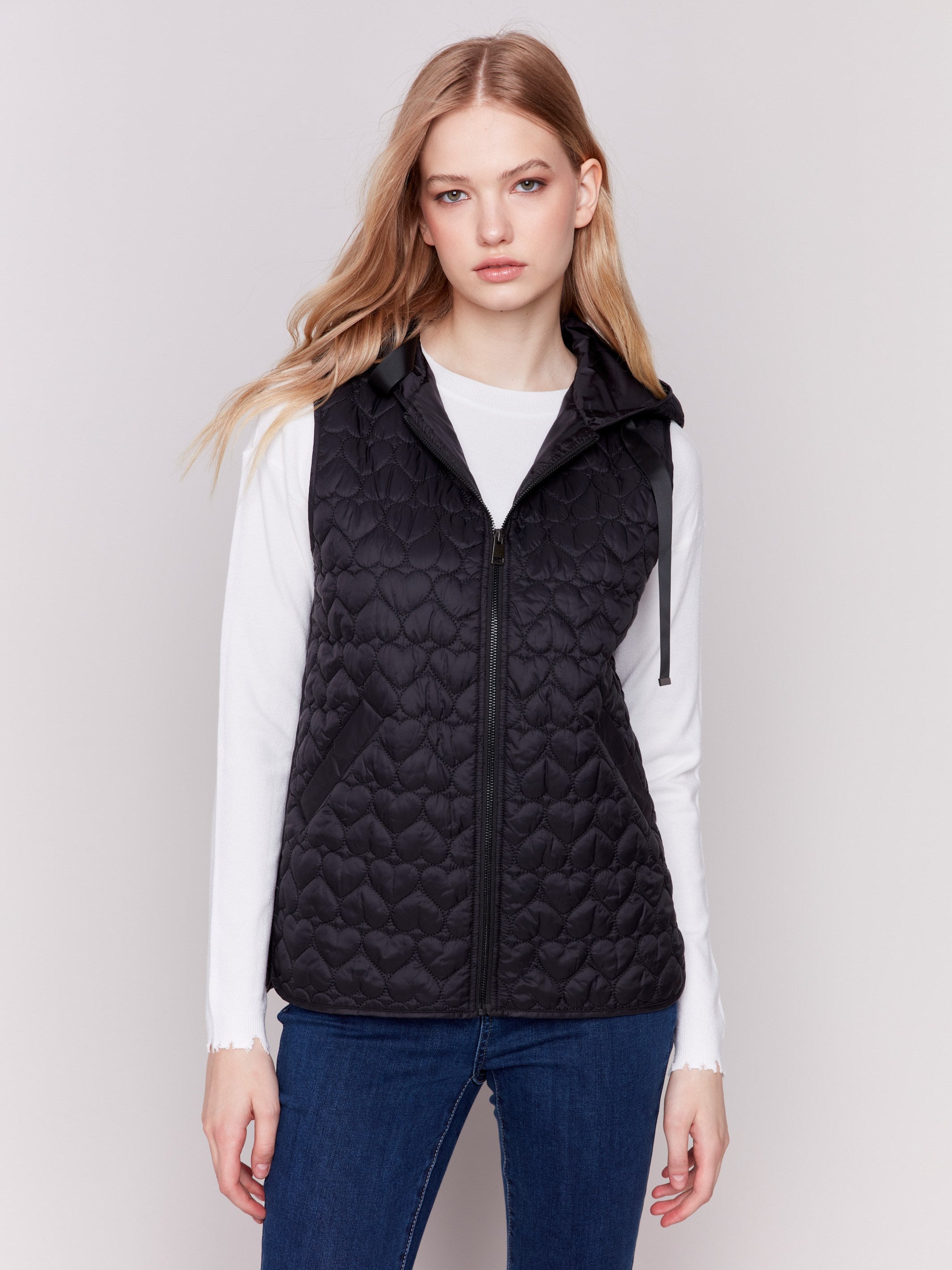 Black short quilted puffer vest with a hood, featuring a mini heart pattern and front pockets by Charlie B.