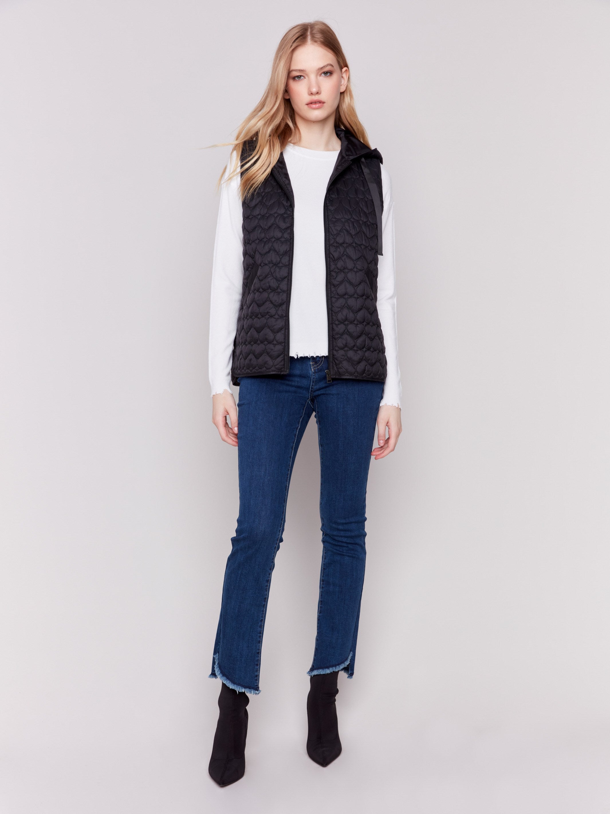 Black short quilted puffer vest with a hood, featuring a mini heart pattern and front pockets by Charlie B.