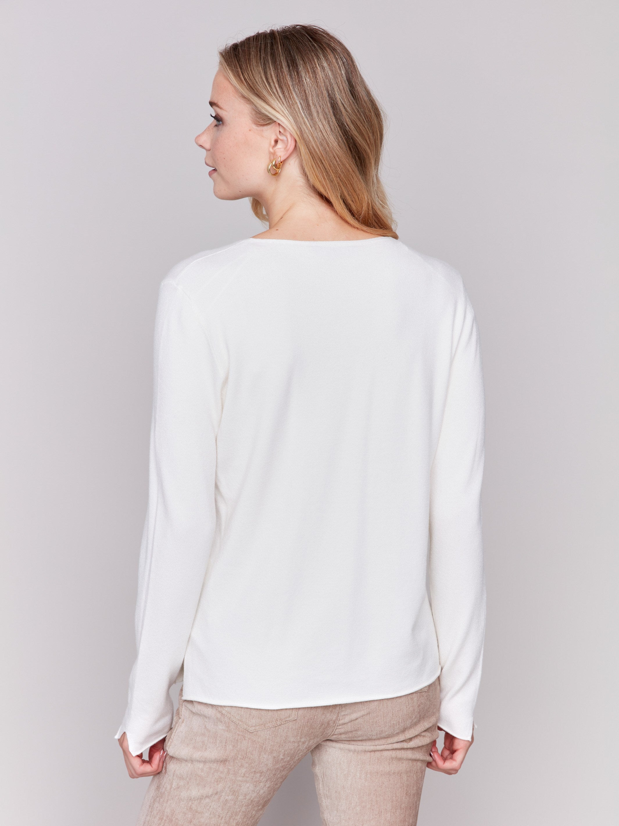 Ecru white V-neck sweater with long sleeves featuring side slits, made from plushy yarn by Charlie B.