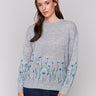 Grey knit sweater with blue floral embroidery along the hem and sleeves, featuring a crew neckline by Charlie B.