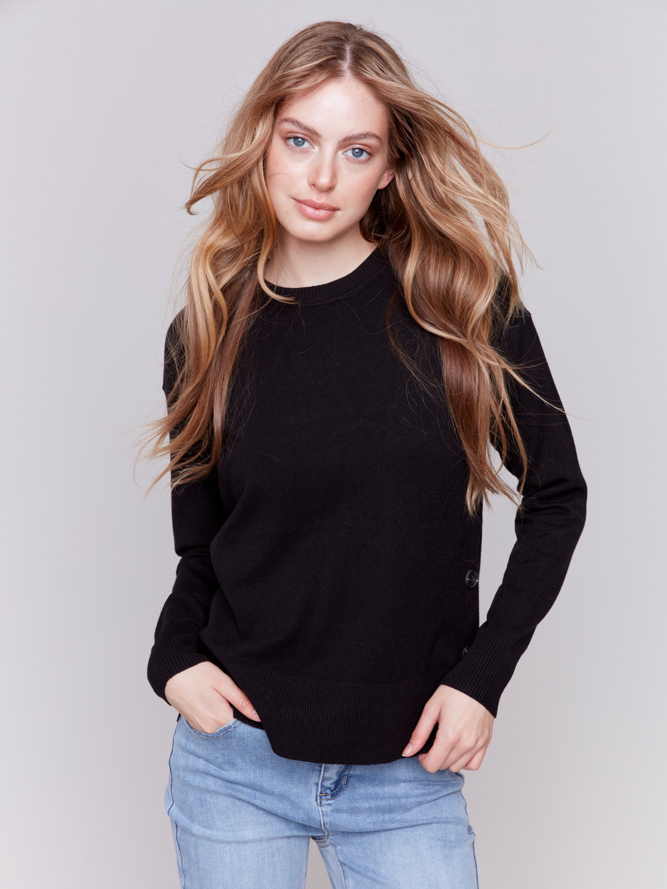 Black sweater with long sleeves and side button detailing by Charlie B.