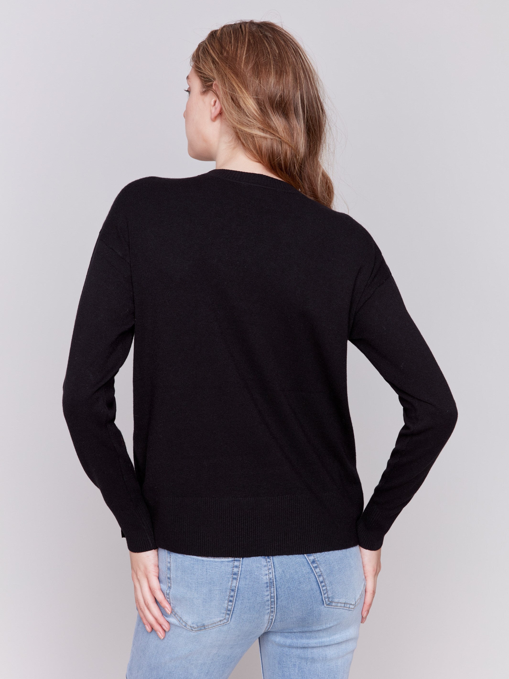 Black sweater with long sleeves and side button detailing by Charlie B.