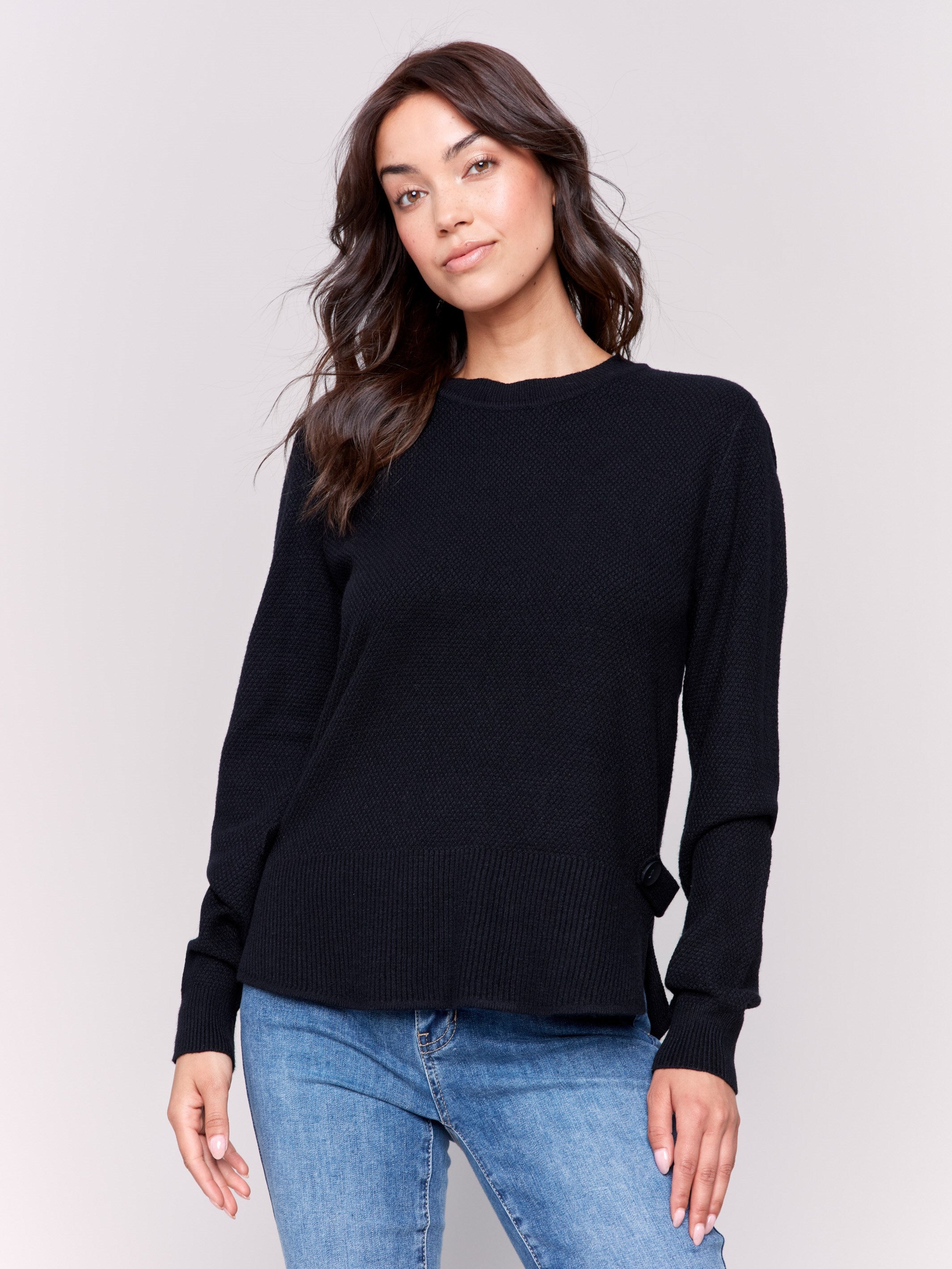 Black sweater with long sleeves featuring side tab details and a round hem by Charlie B.