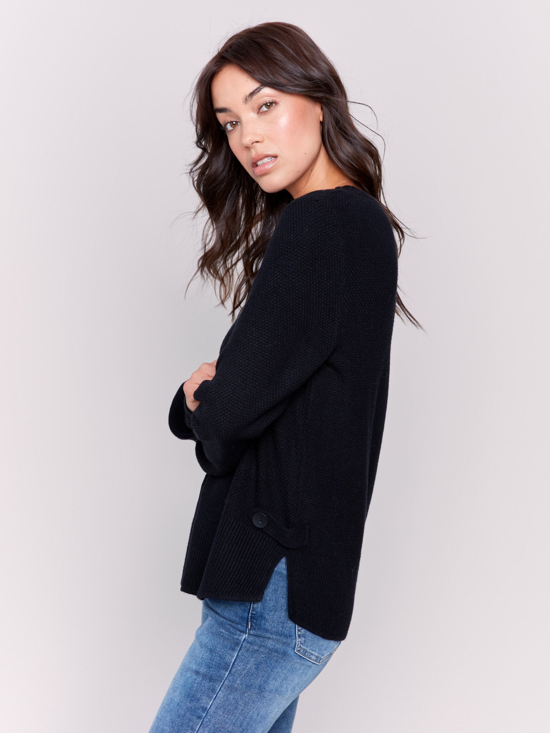 Black sweater with long sleeves featuring side tab details and a round hem by Charlie B.