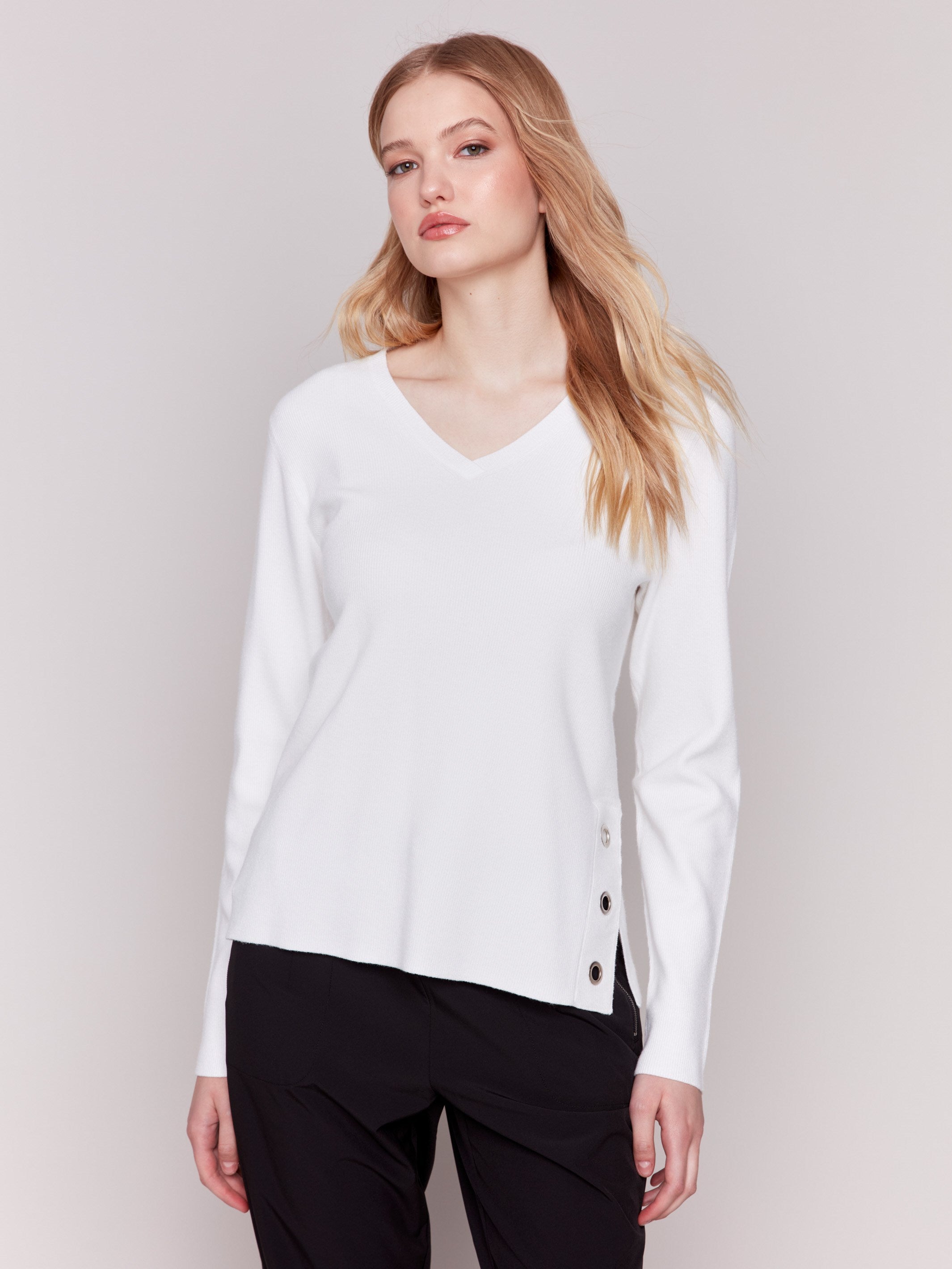 Cream-colored V-neck sweater with long sleeves featuring grommet details at the side placket by Charlie B.