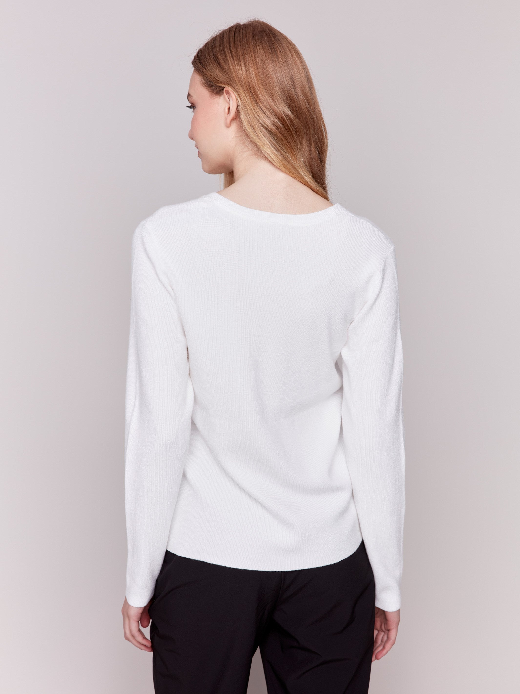 Cream-colored V-neck sweater with long sleeves featuring grommet details at the side placket by Charlie B.